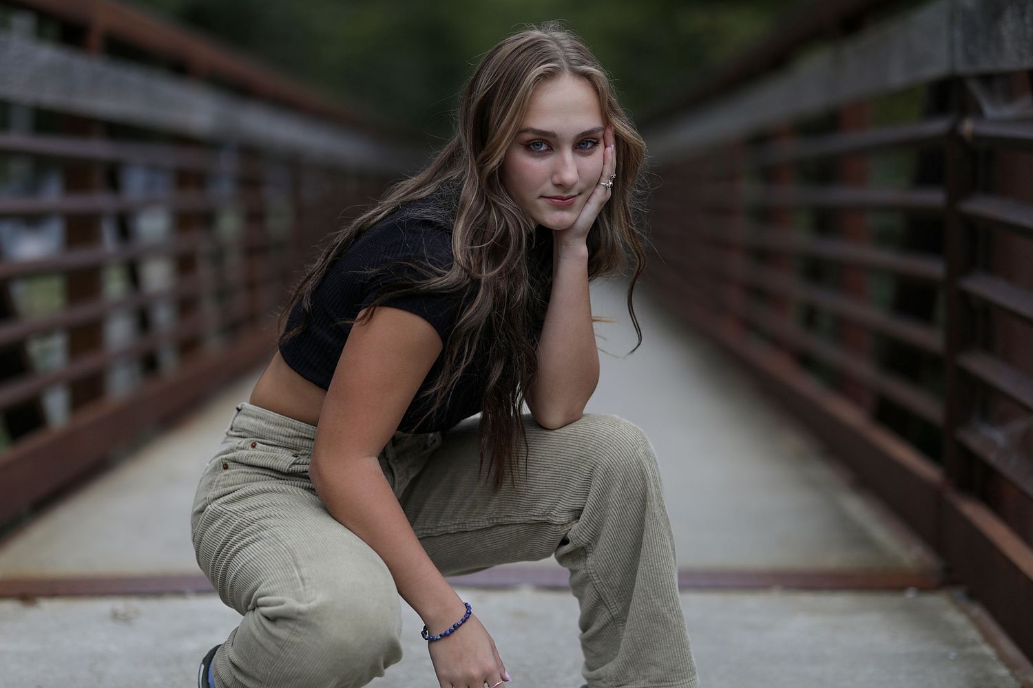 Outdoor portrait photography session on a wooden walkway surrounded by rustic railing.