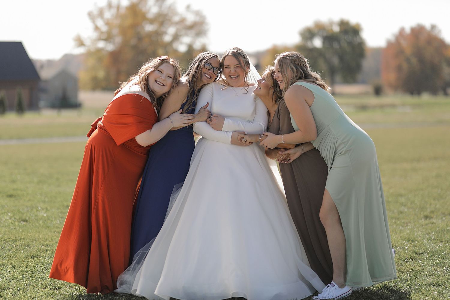A joyful gathering of people in formal attire share an intimate moment outdoors.