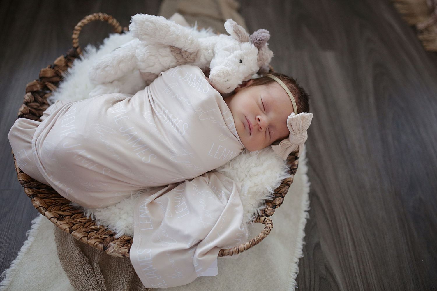 Newborn dressed in white lace gown resting peacefully on white blanket in vintage antique inspired photography.