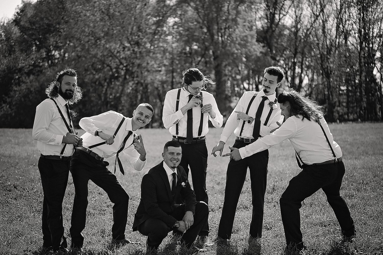 Groomsmen pose playfully in black and white for a fun wedding photo.