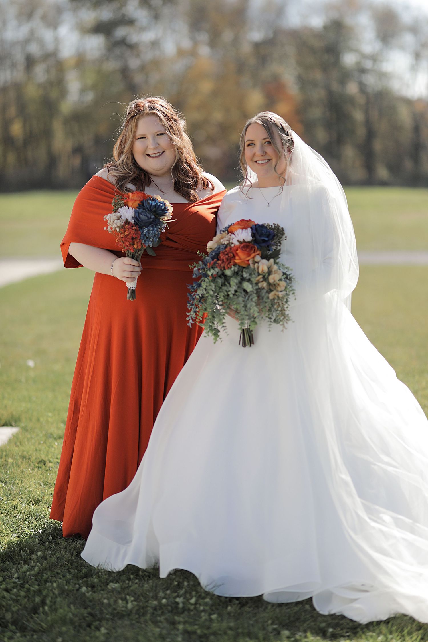 Bridesmaids in vibrant orange dresses pose with bride in flowing white gown.