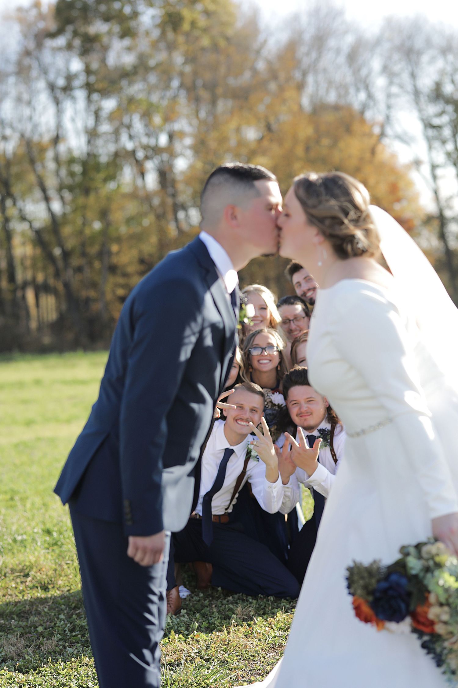 Wedding party celebrates joyfully during an outdoor autumn ceremony.
