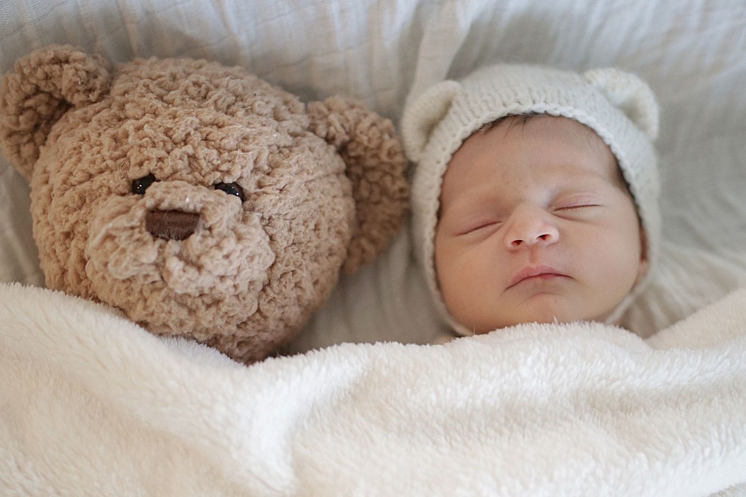 Five sequential images show a baby sleeping peacefully in white bedding next to a brown teddy bear.