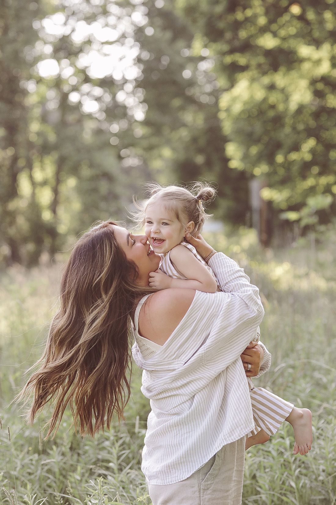 Mother and child playing together in sunny summer field with joyful expressions.