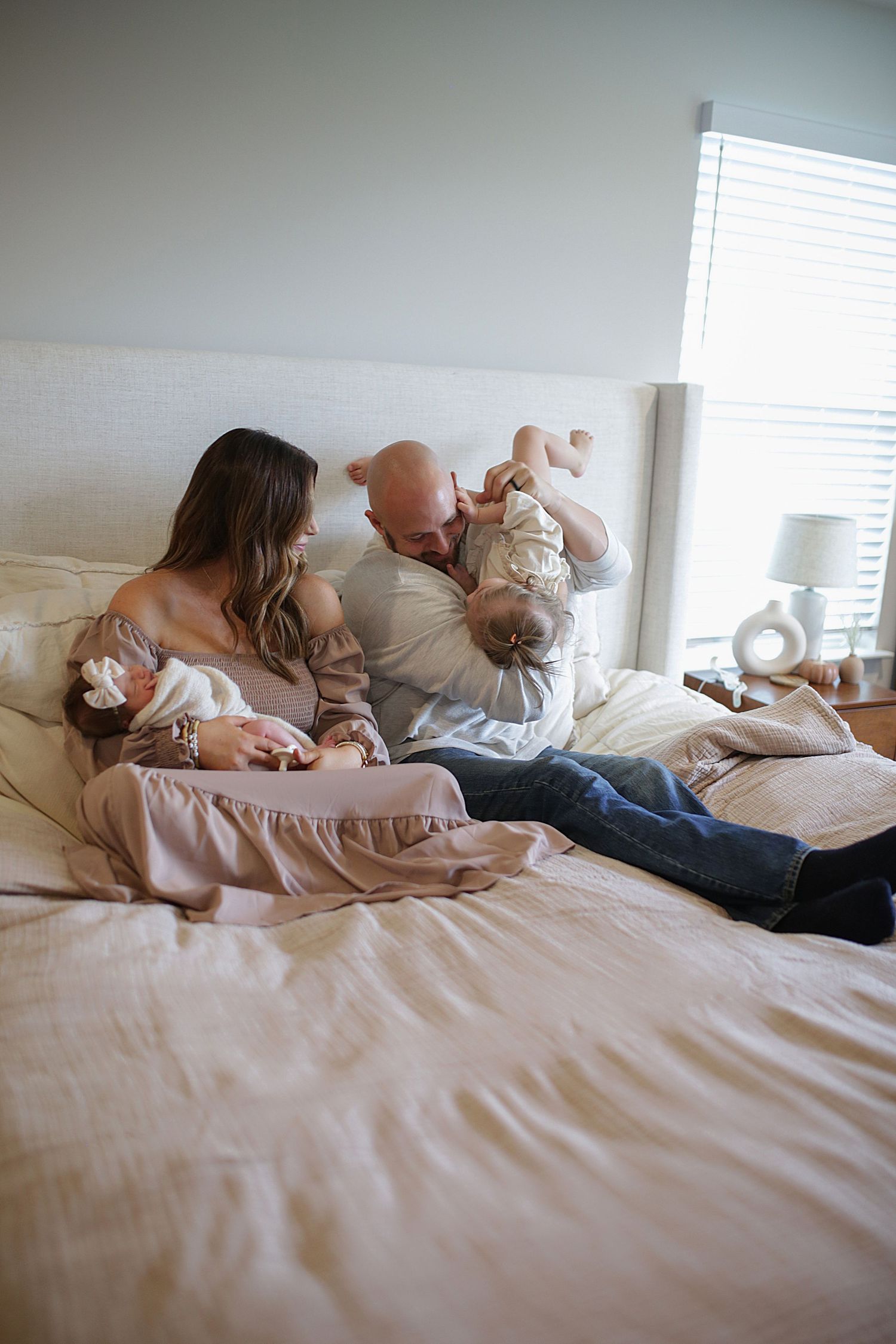 A sequence of photos shows a tender family moment as they relax together on white bedding in natural light.