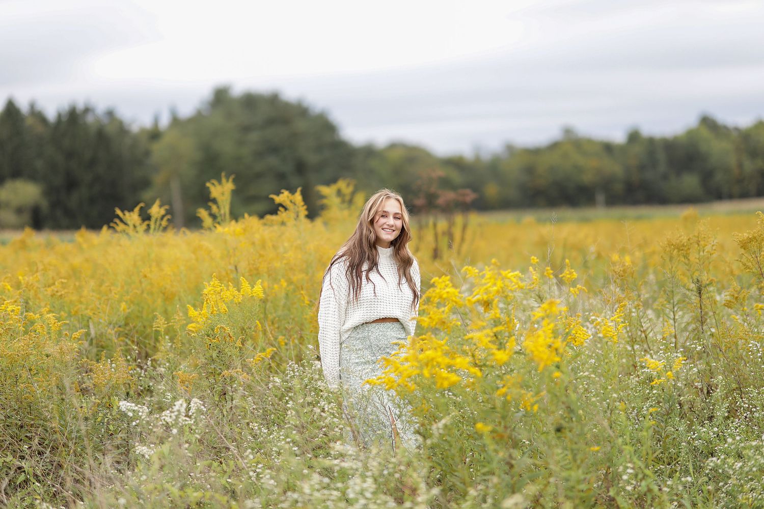 Series of outdoor portrait photos taken in a field of vibrant yellow wildflowers with overcast skies in the background.