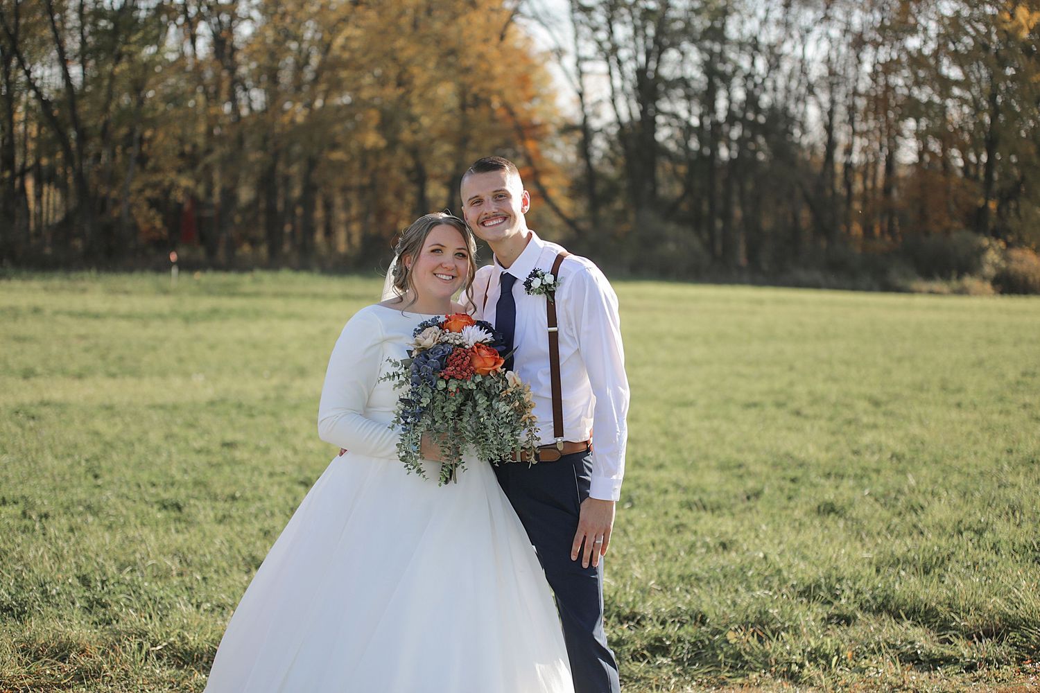 Couple shares intimate wedding moments in a sun-lit autumn field.