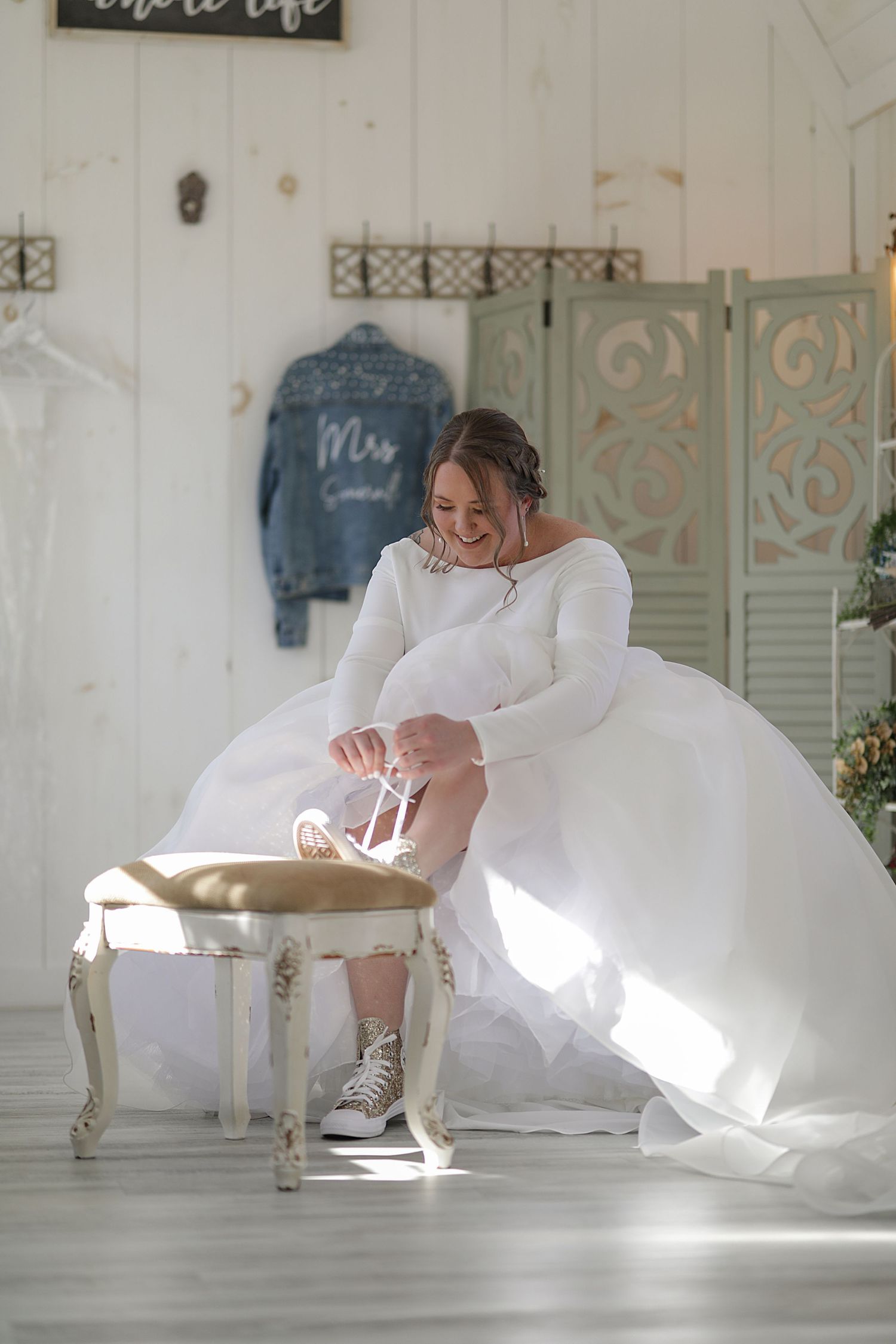 Wedding dress billowing dramatically in a bright sunlit white room.