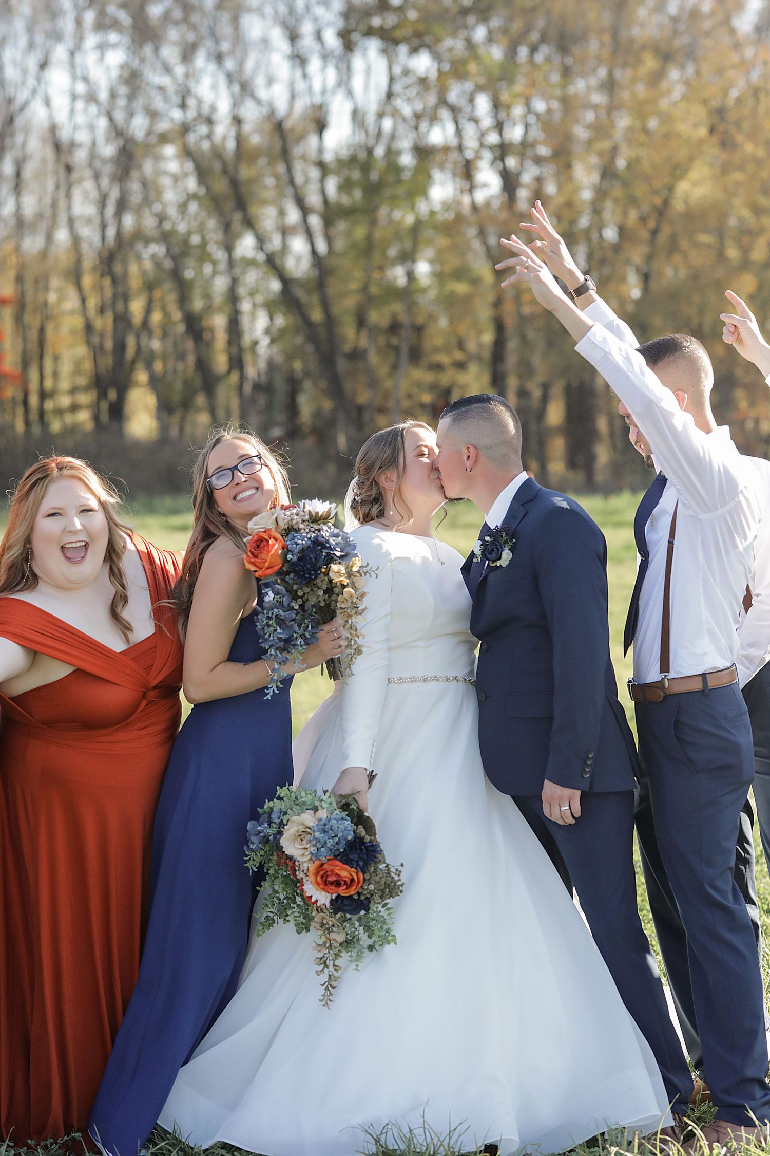 Wedding party celebrates with bridal couple outdoors during fall season celebration.