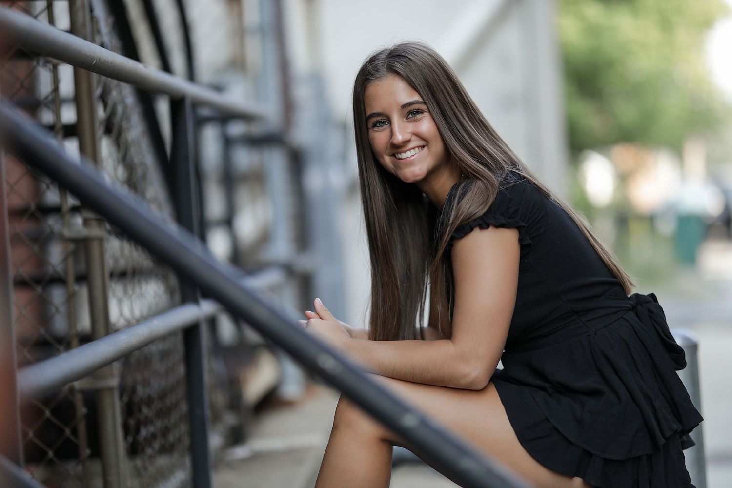 Woman in black dress poses on bridge in outdoor portrait series.