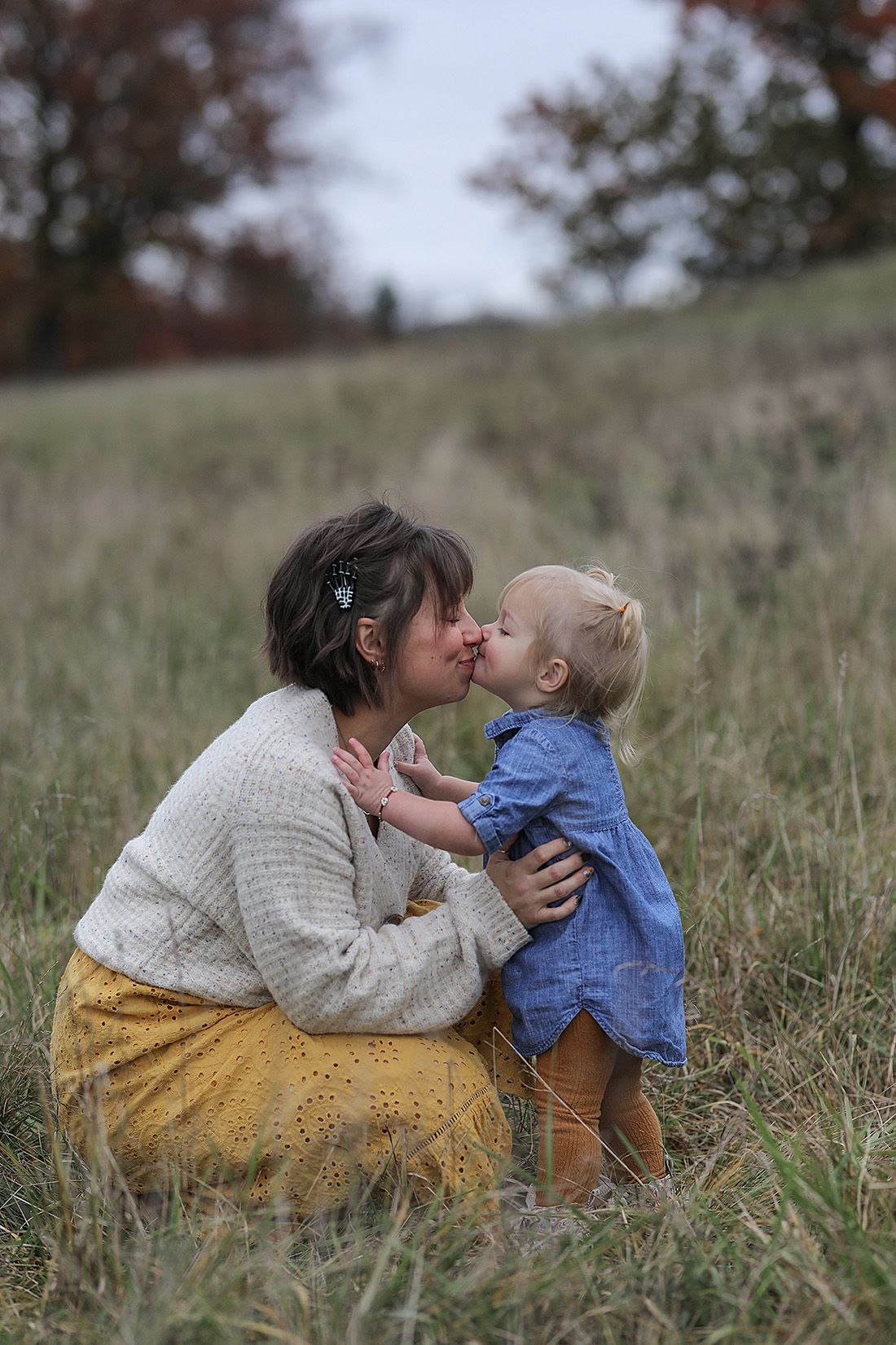 Intimate mother-child portraits in rustic field wearing cozy knits and mustard skirt.