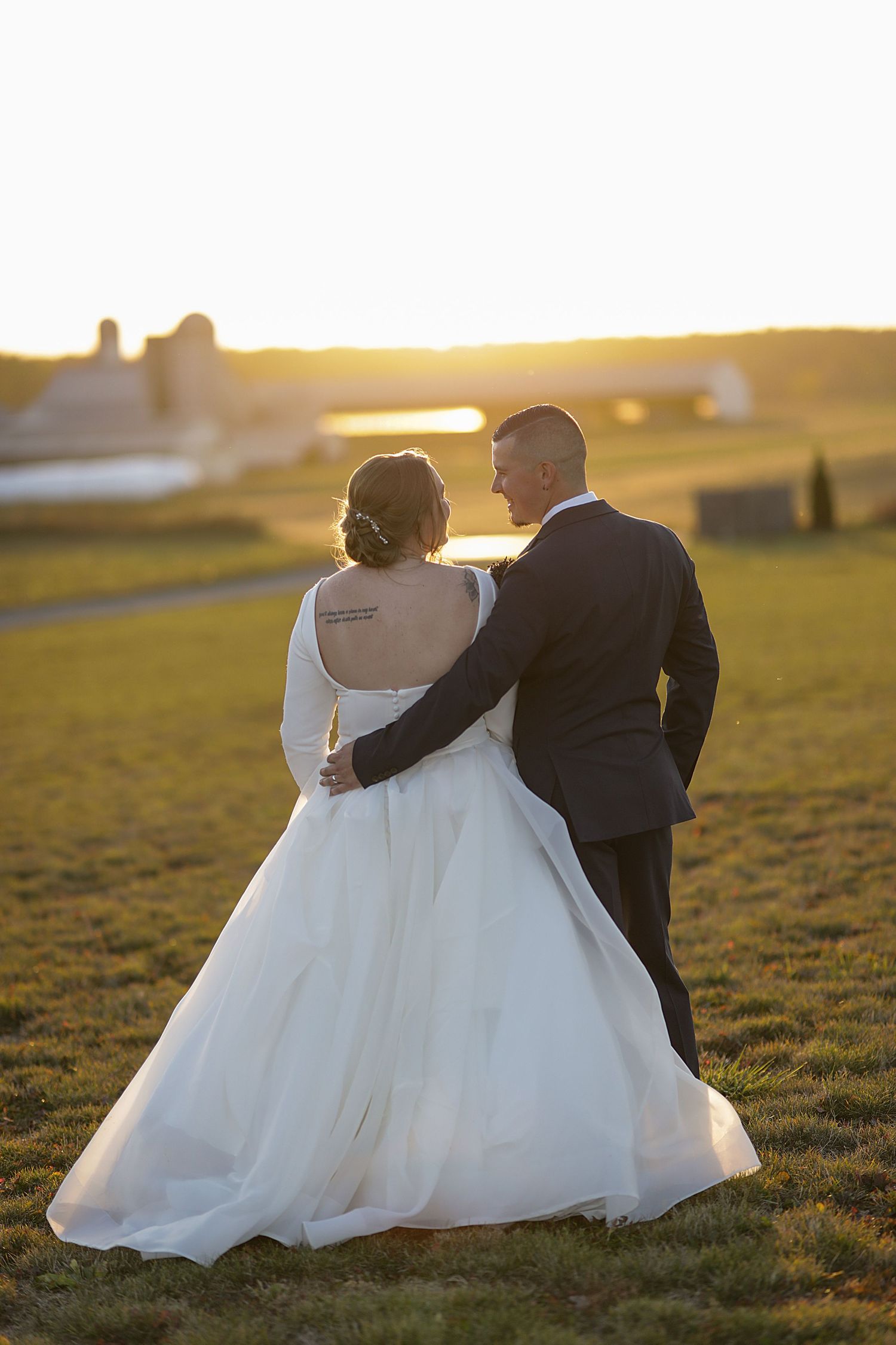 Wedding couple shares intimate moment at sunset in an outdoor setting with glowing golden light.