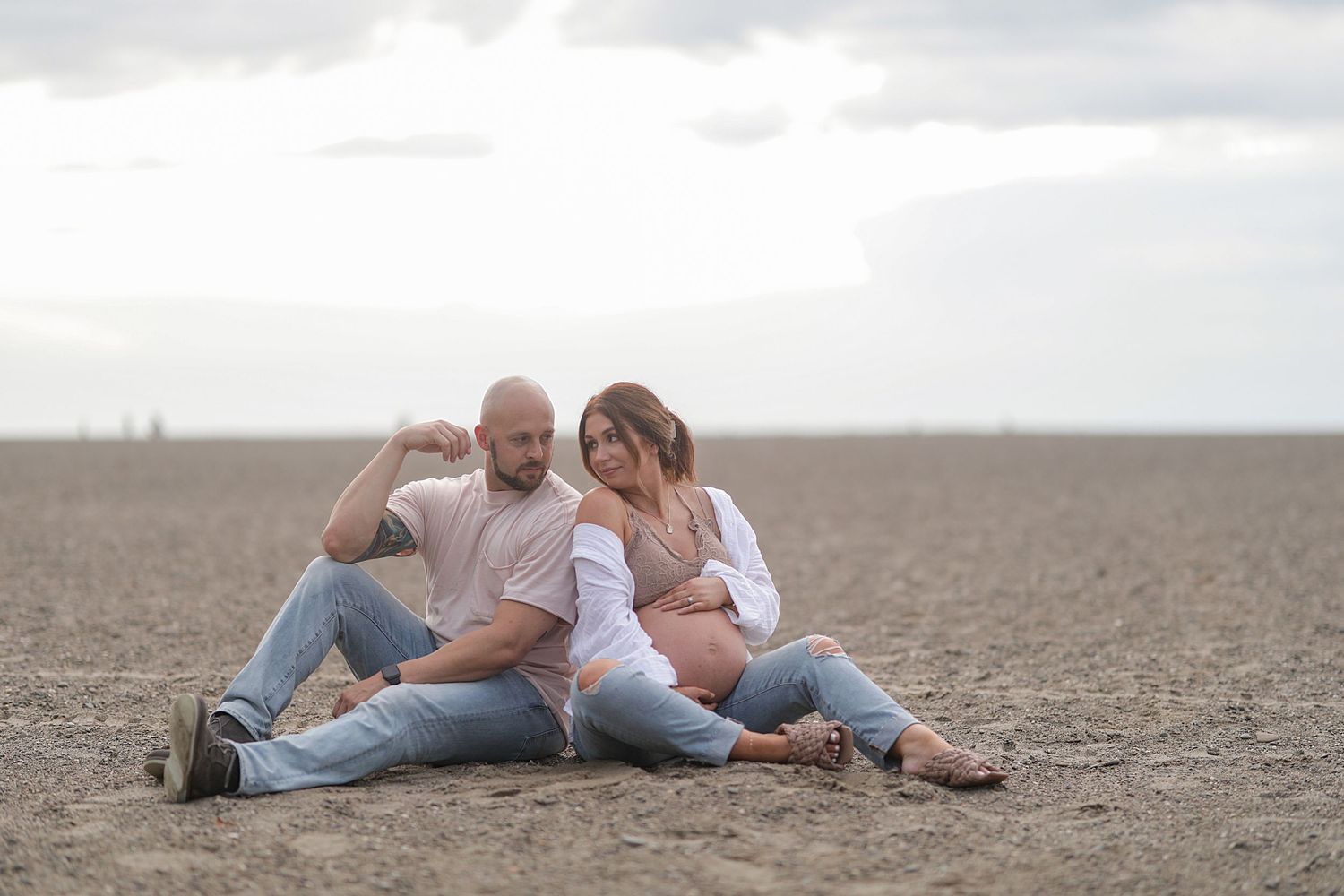 Couple sharing intimate moments while lying on brown soil in a serene outdoor setting.