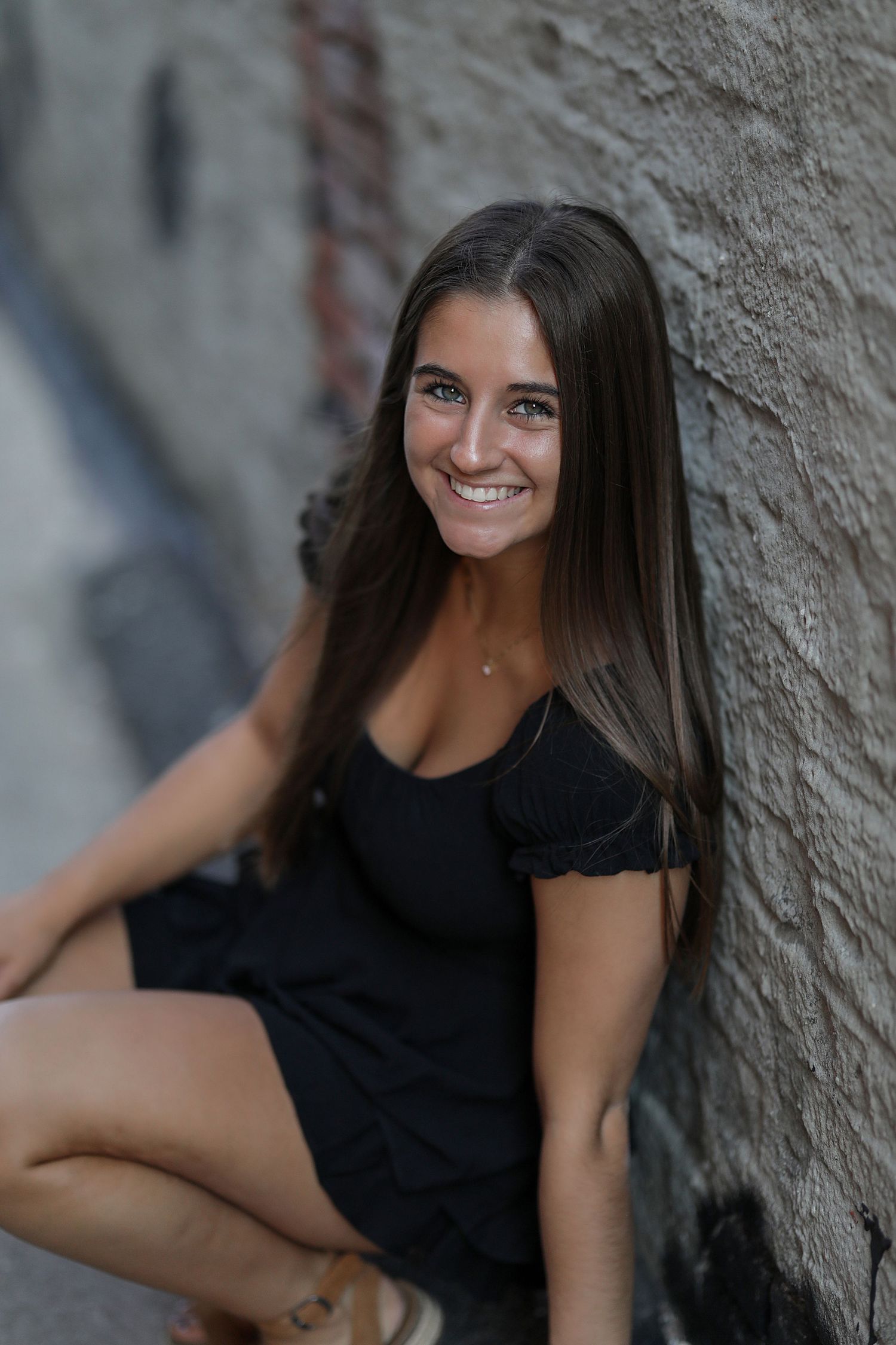 A person in a black top poses against a textured wall in a series of casual portrait shots.