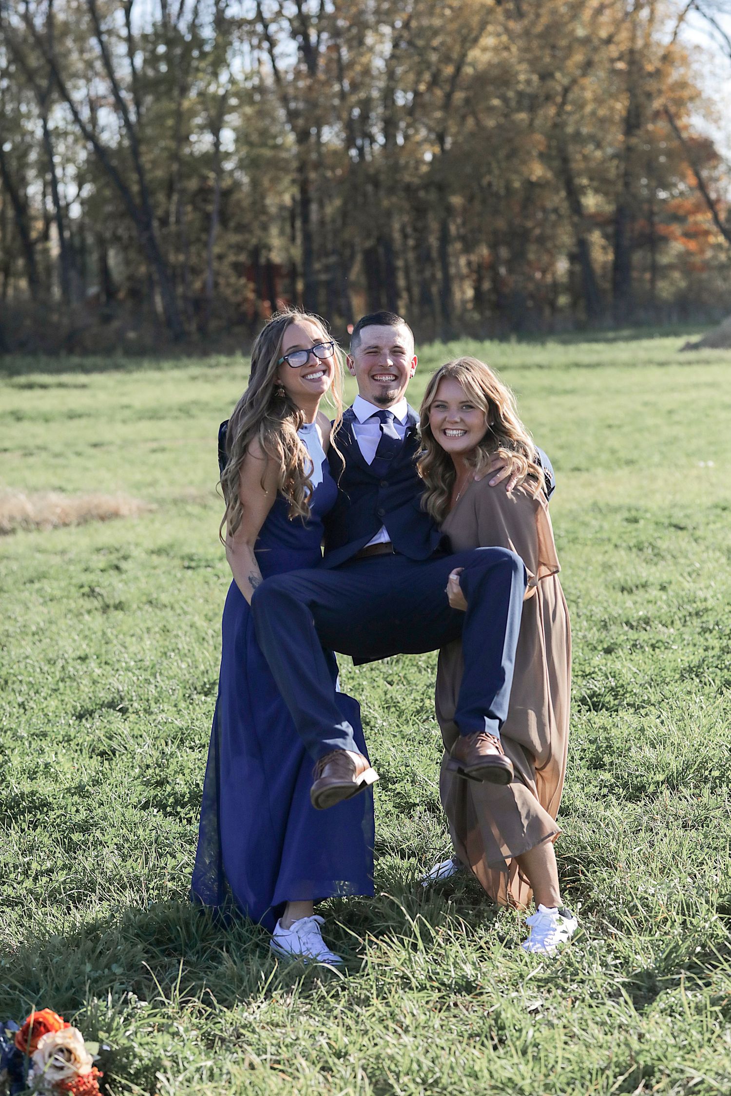Playful wedding party photo shoot in a grassy autumn field.