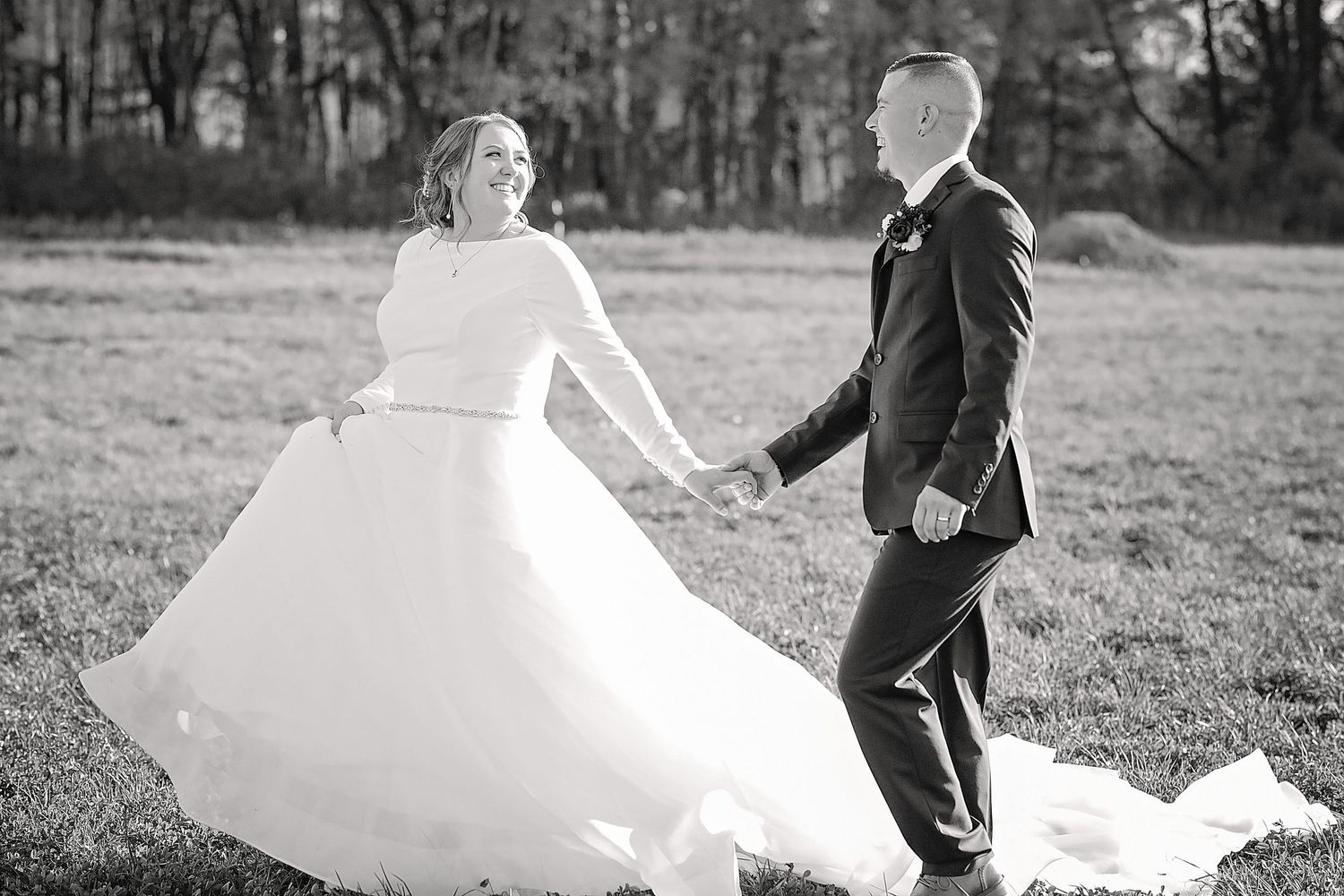 Wedding couple dancing and twirling in field during autumn photoshoot.