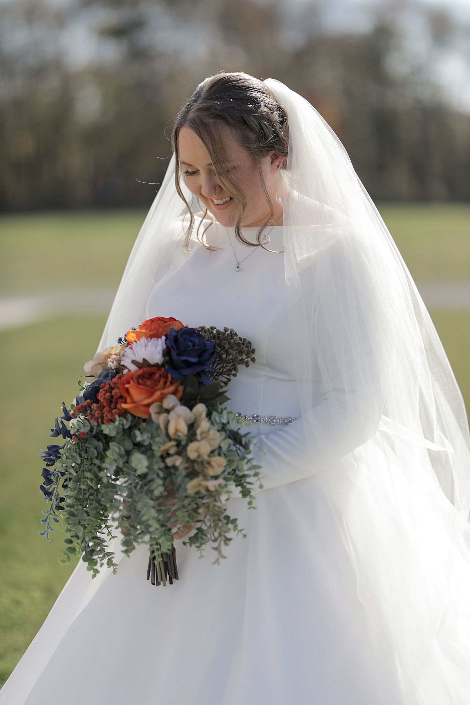 Close-up of a bridal bouquet featuring orange, blue and green florals with eucalyptus.