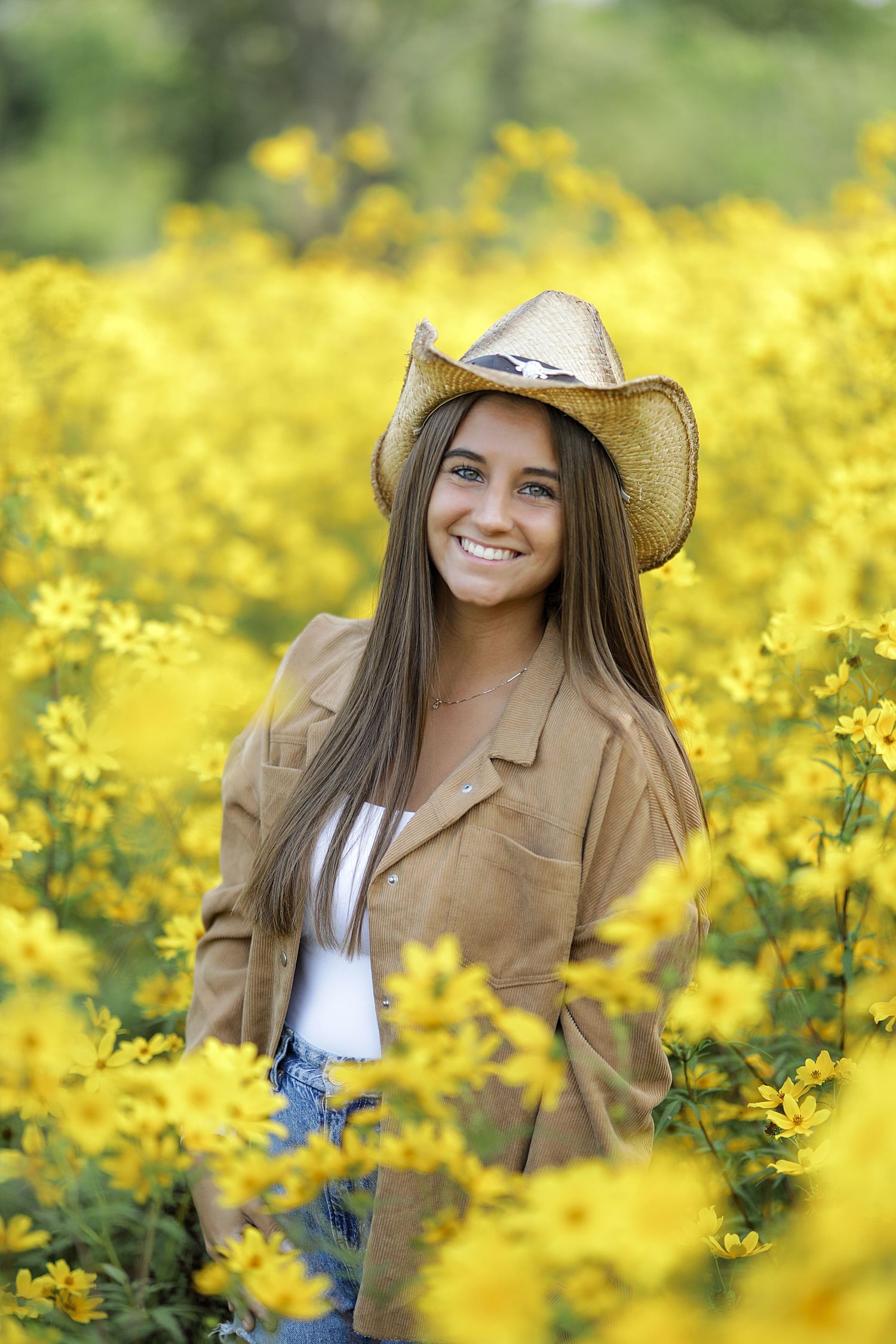 A cowboy hat and brown jacket stand out among vibrant yellow wildflowers in a sunny meadow.