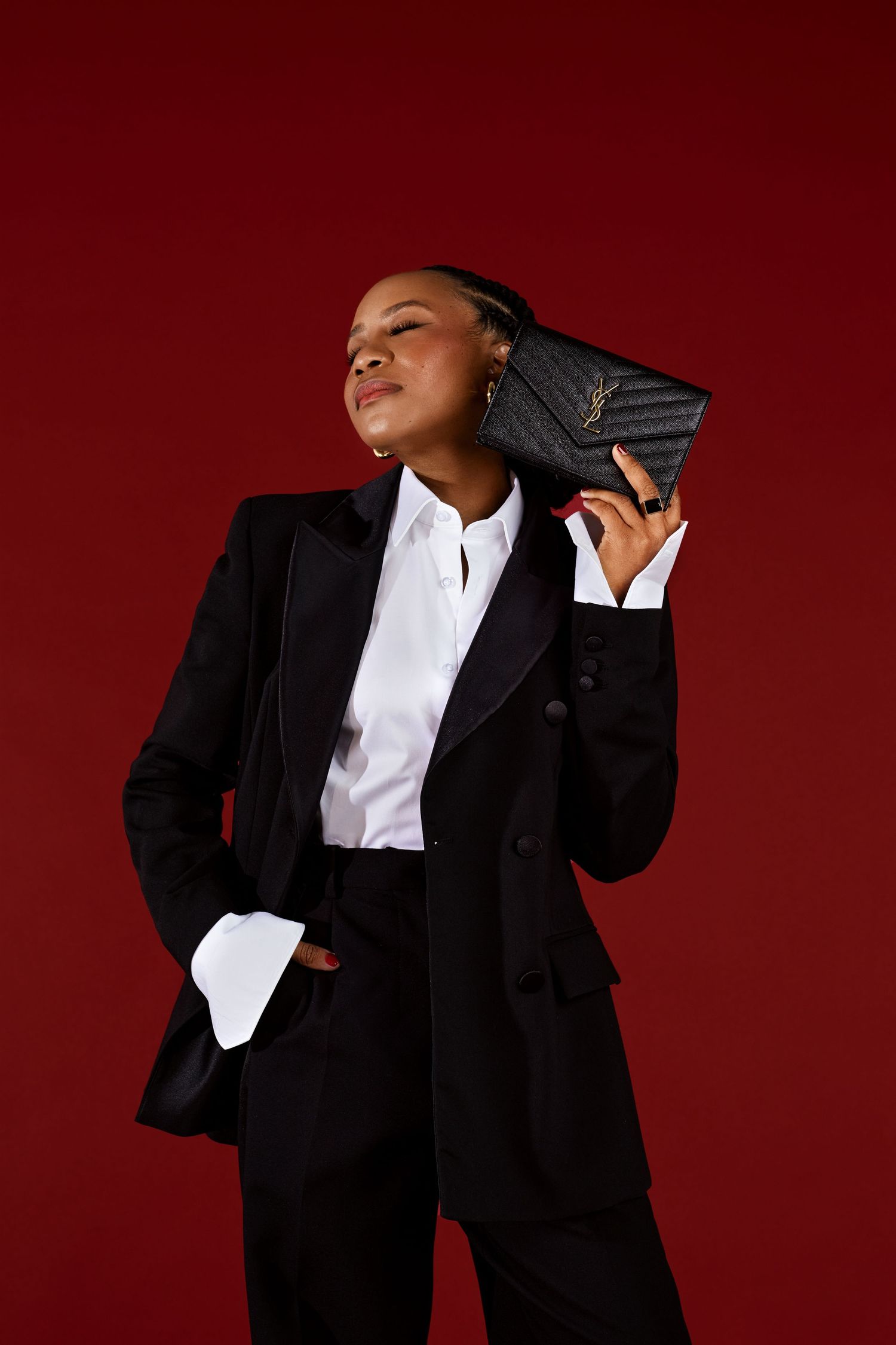 Dramatic fashion poses in black blazer and white shirt against deep red background.