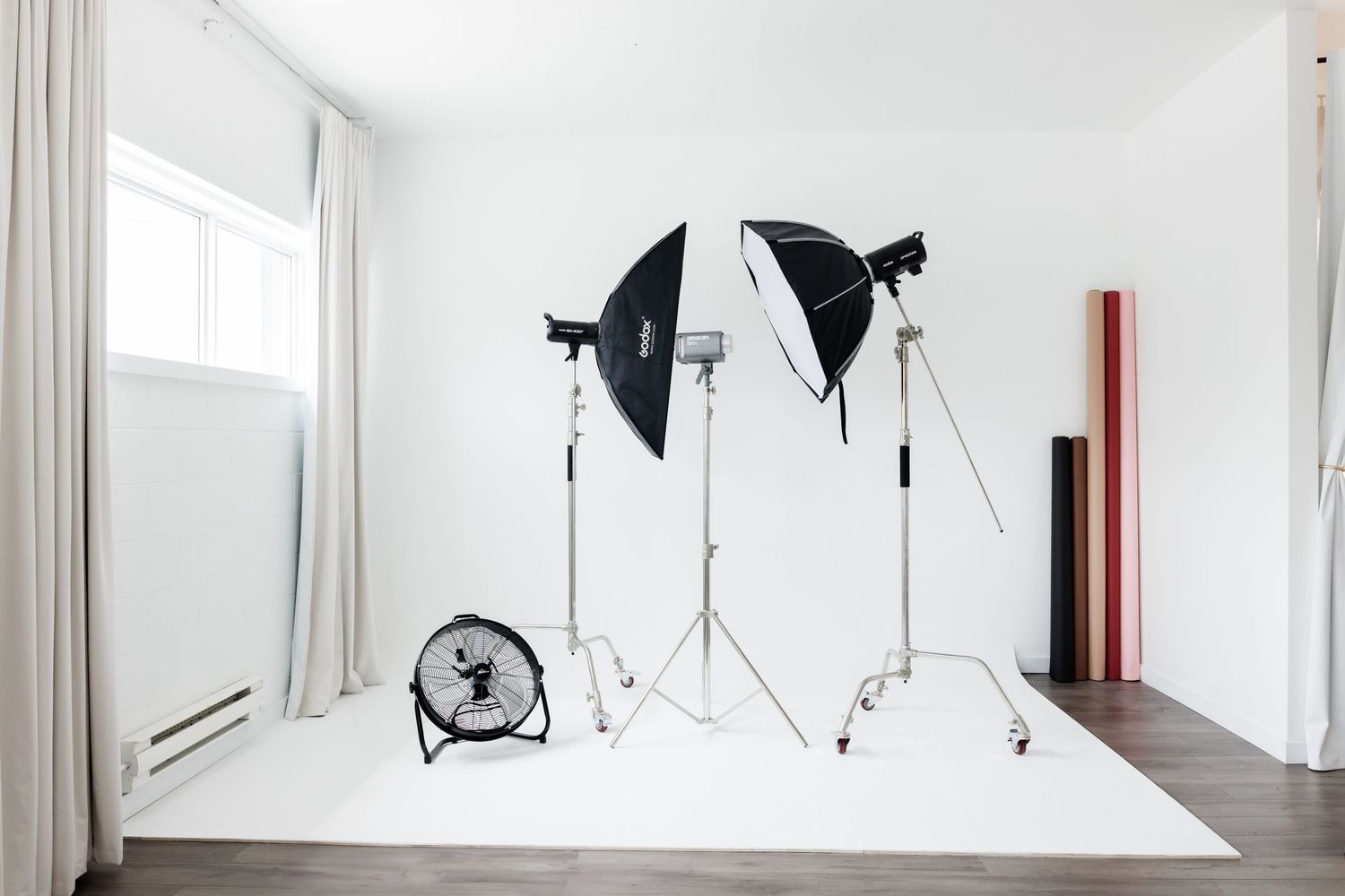 White studio space with professional photography lighting equipment and backdrop.