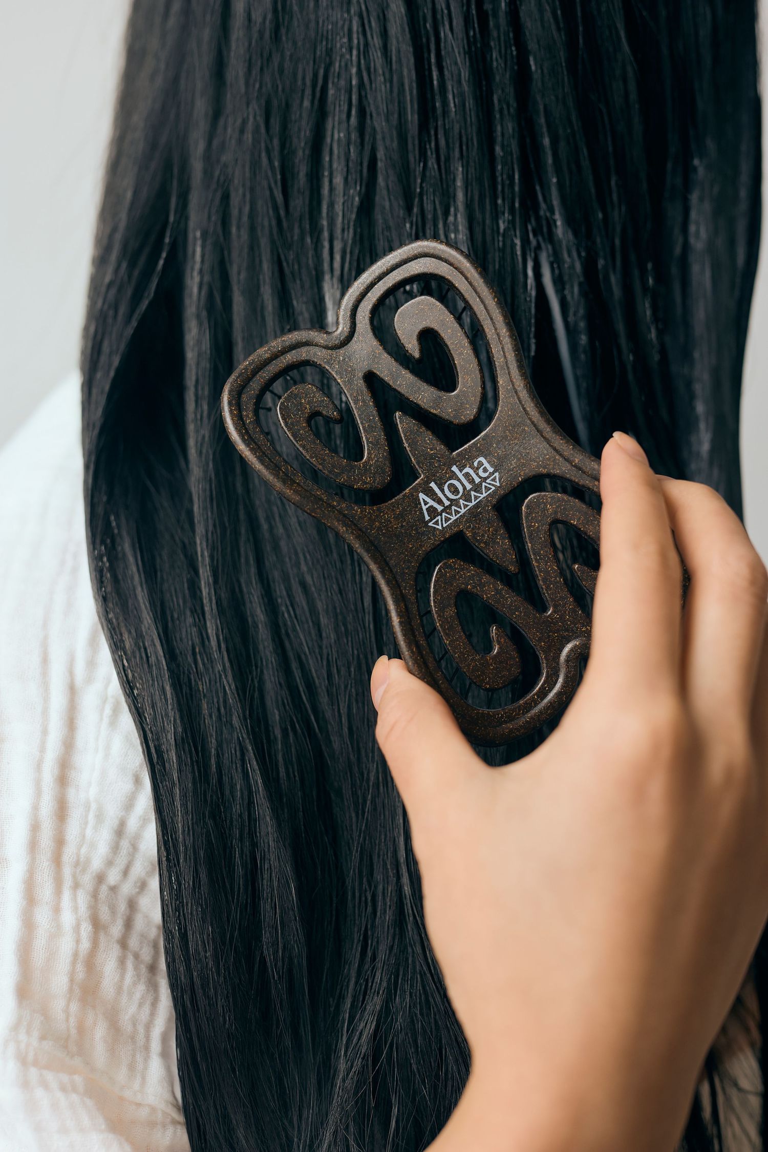 Close up of hand holding dark hair brush through long black hair.
