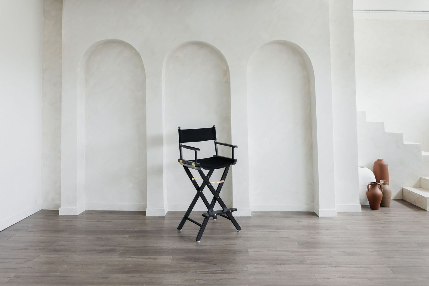 Director's chair positioned against white wall with arched alcoves.