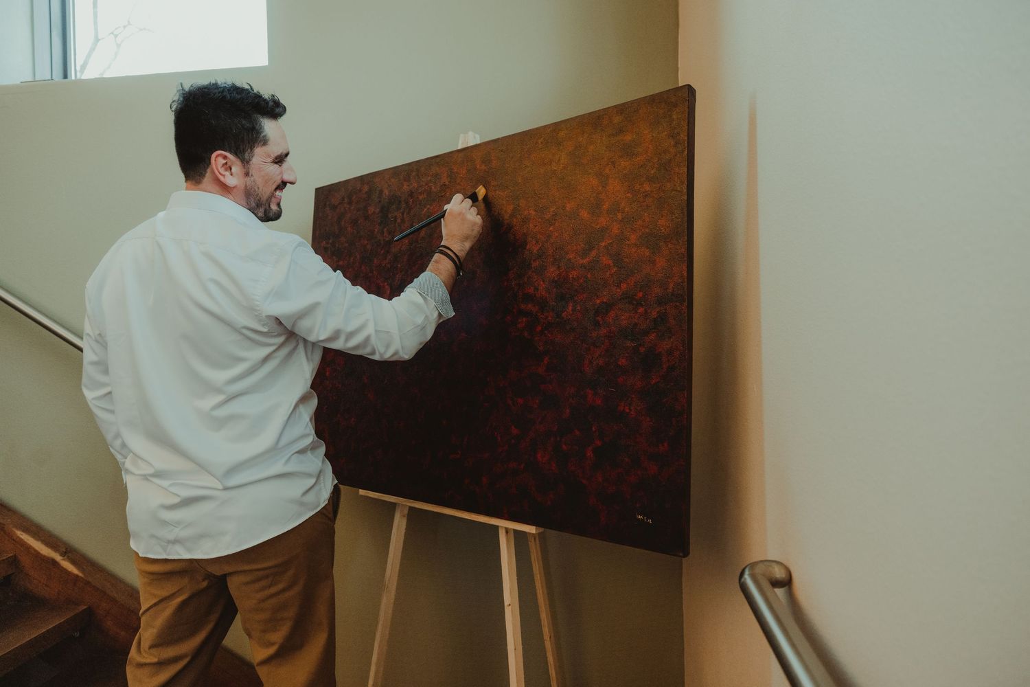 People installing red damask wallpaper on an interior wall.
