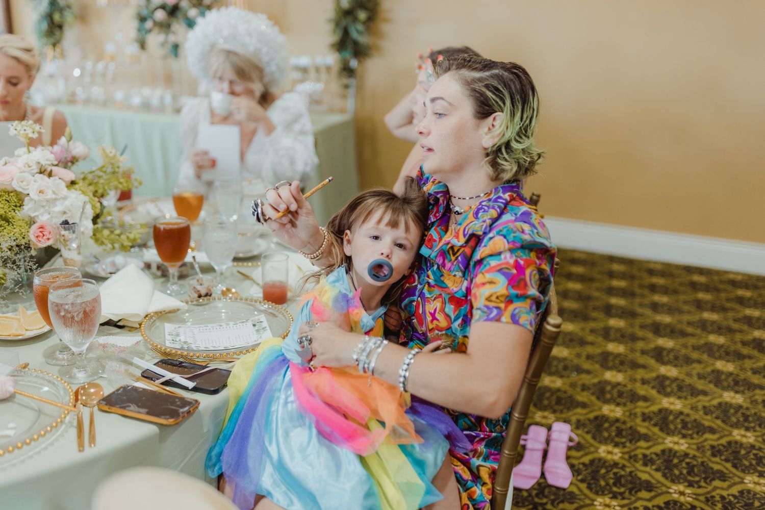 A joyful moment of laughter at a colorful dining table decorated with floral arrangements.