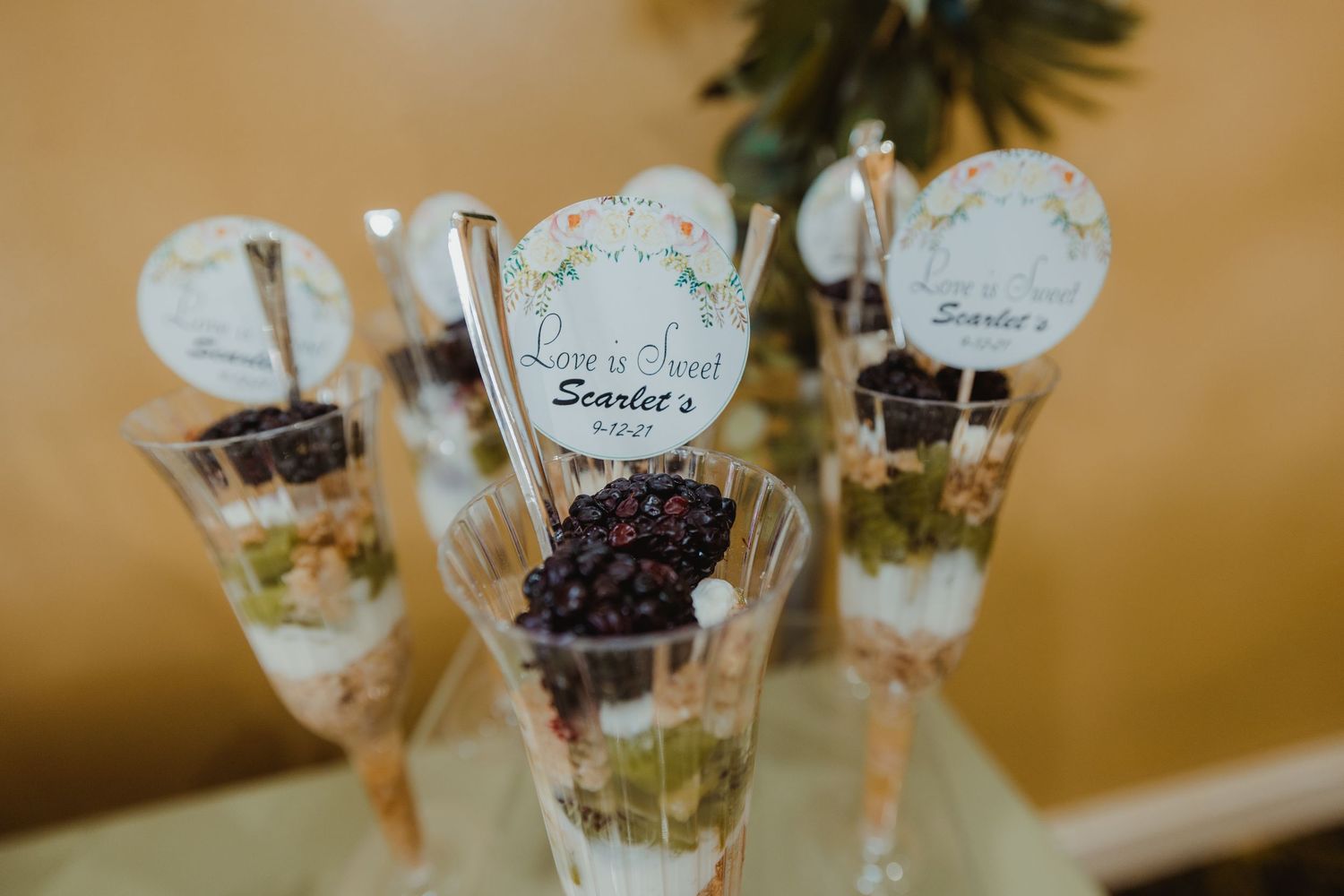 Elegant dessert shooters with layered ingredients and name cards featuring chocolate crumbles and pistachio toppings.