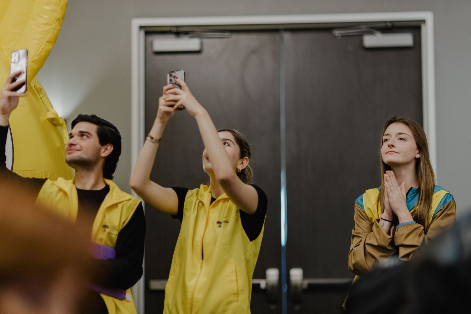 Excited sports fans in yellow jerseys cheer enthusiastically while watching a game together.