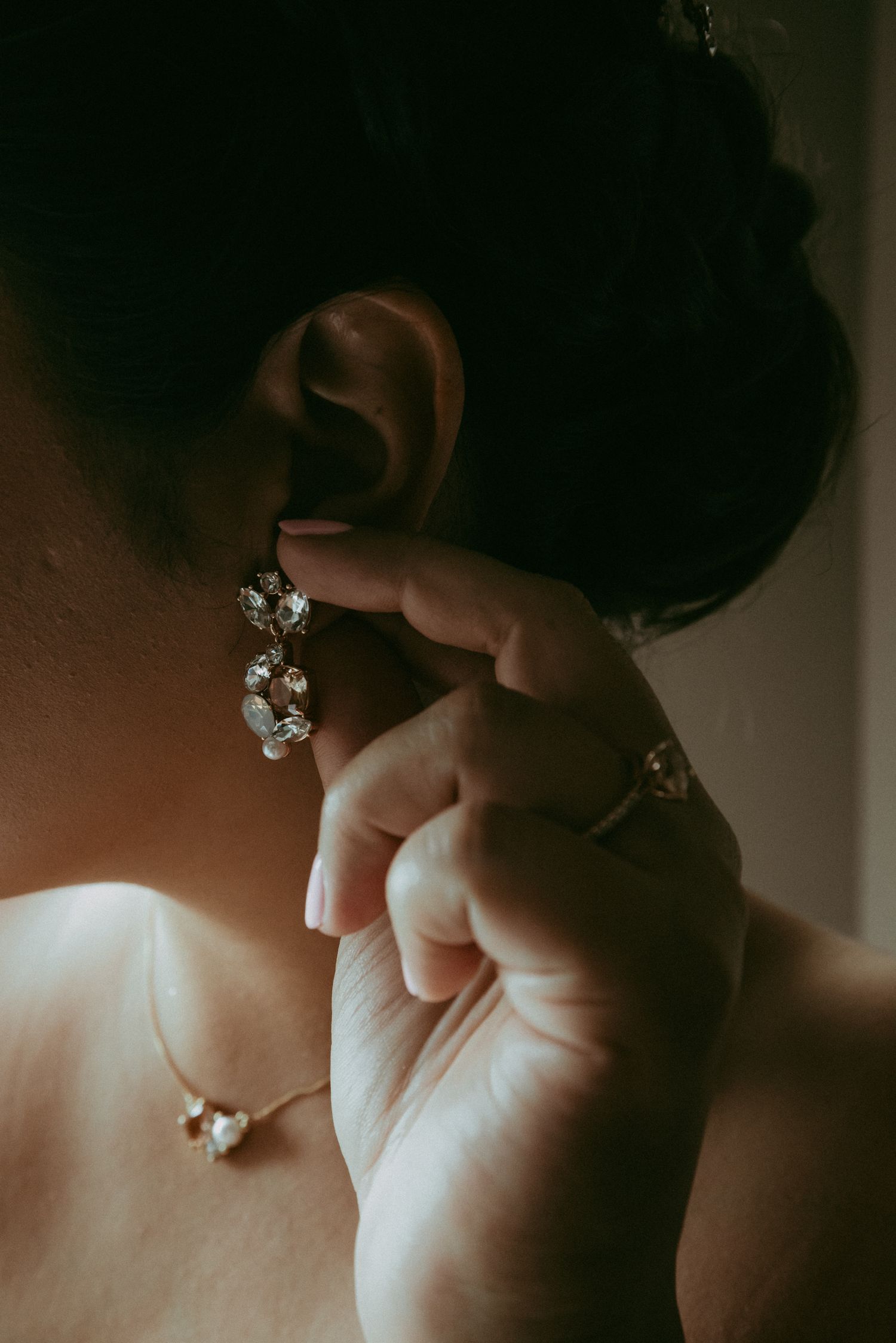 Close-up shot of sparkly diamond earring being adjusted on ear.