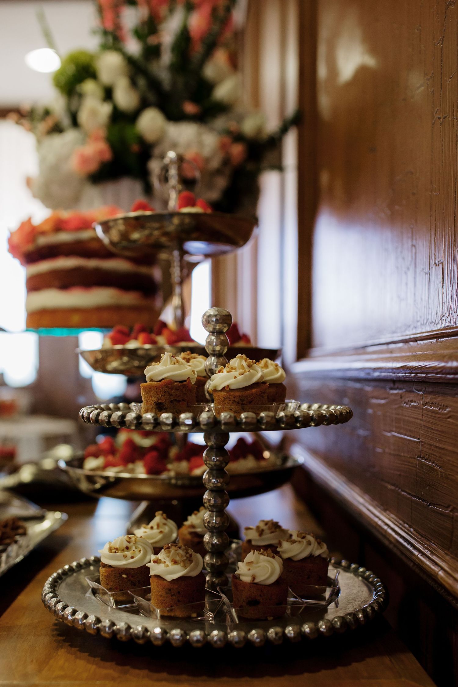 A rustic tiered serving platter with decorative edging displays assorted desserts and pastries on a wooden surface.