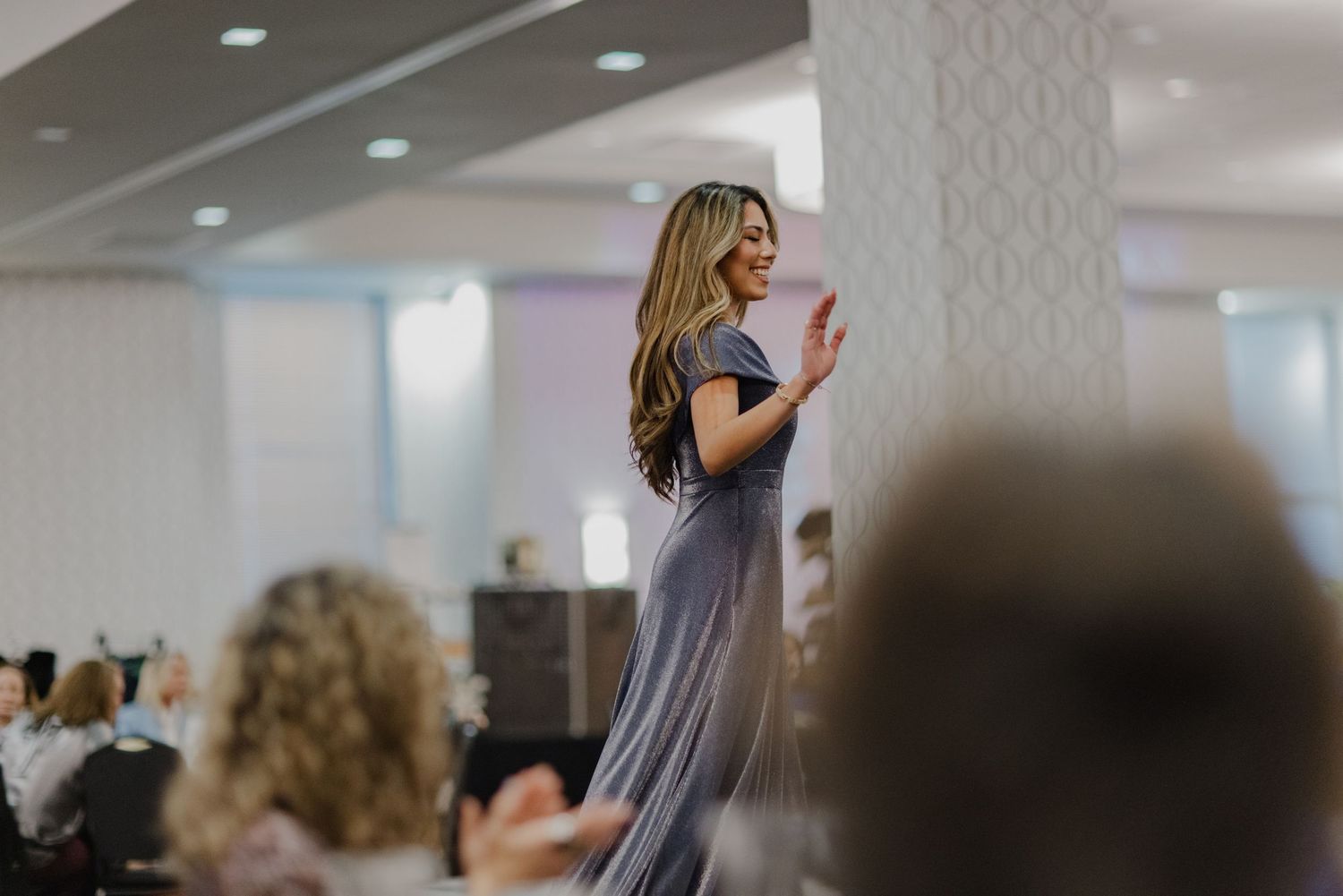 Presenter addressing attendees during conference presentation in modern office meeting space with large screens.