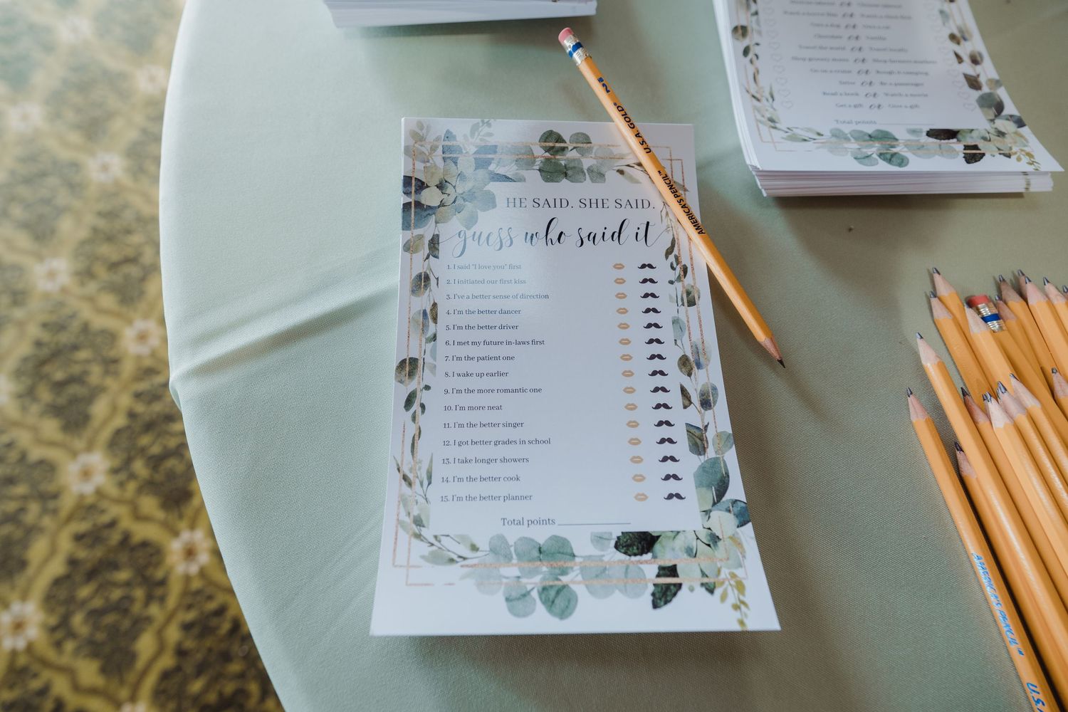 White handcrafted wedding invitations with floral designs and gold pencils on a gray surface being assembled.