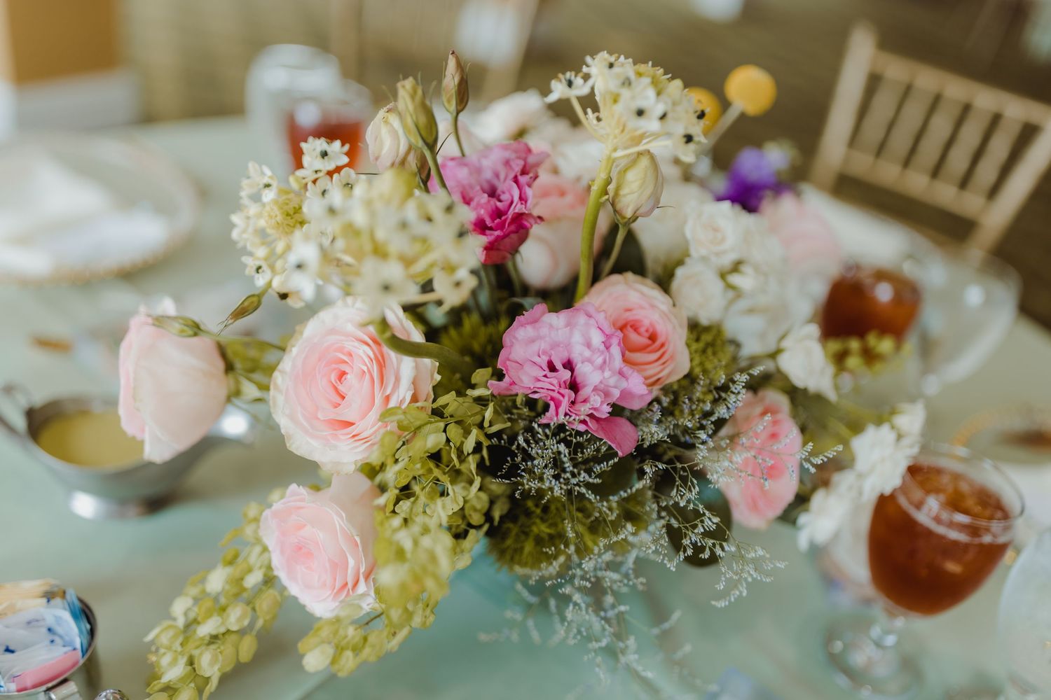 Pink and white floral centerpieces with roses and hydrangeas decorate elegant wedding reception tables.