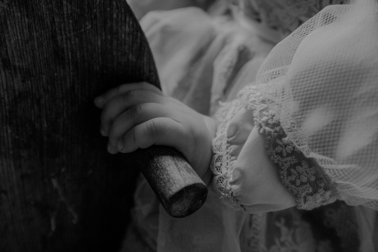 Close-up black and white detail of small hands grasping vintage fabric.