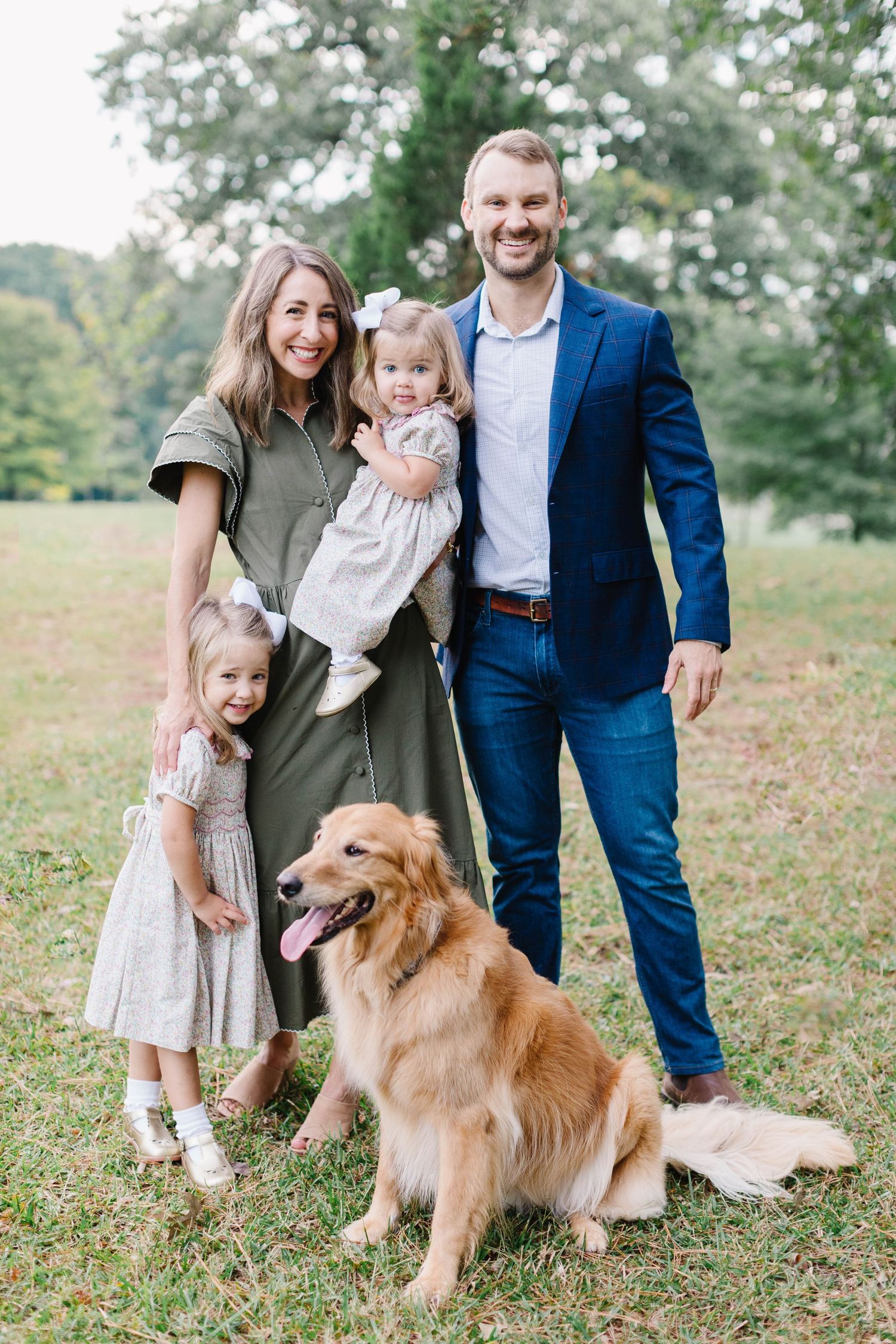 A family poses with their golden retriever dog during an outdoor Atlanta photo session.