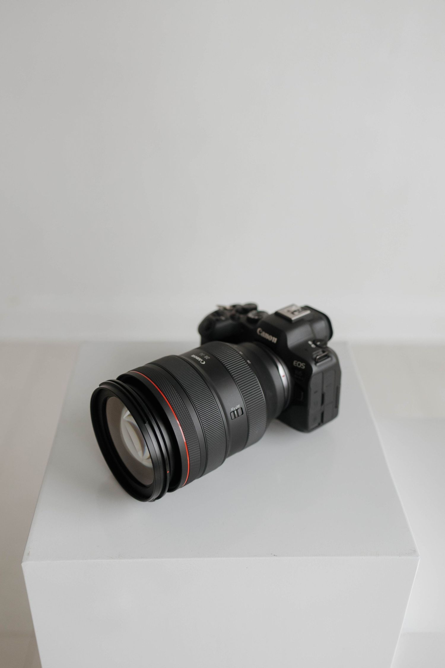 Professional camera with telephoto lens sitting on white surface against neutral background.