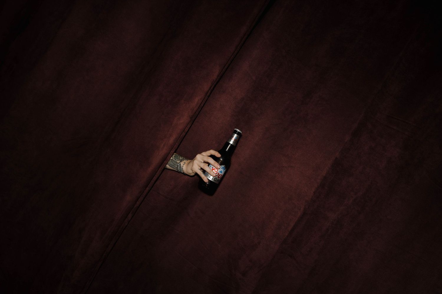 Dark artistic overhead shot of a wine bottle against rich wooden floorboards.