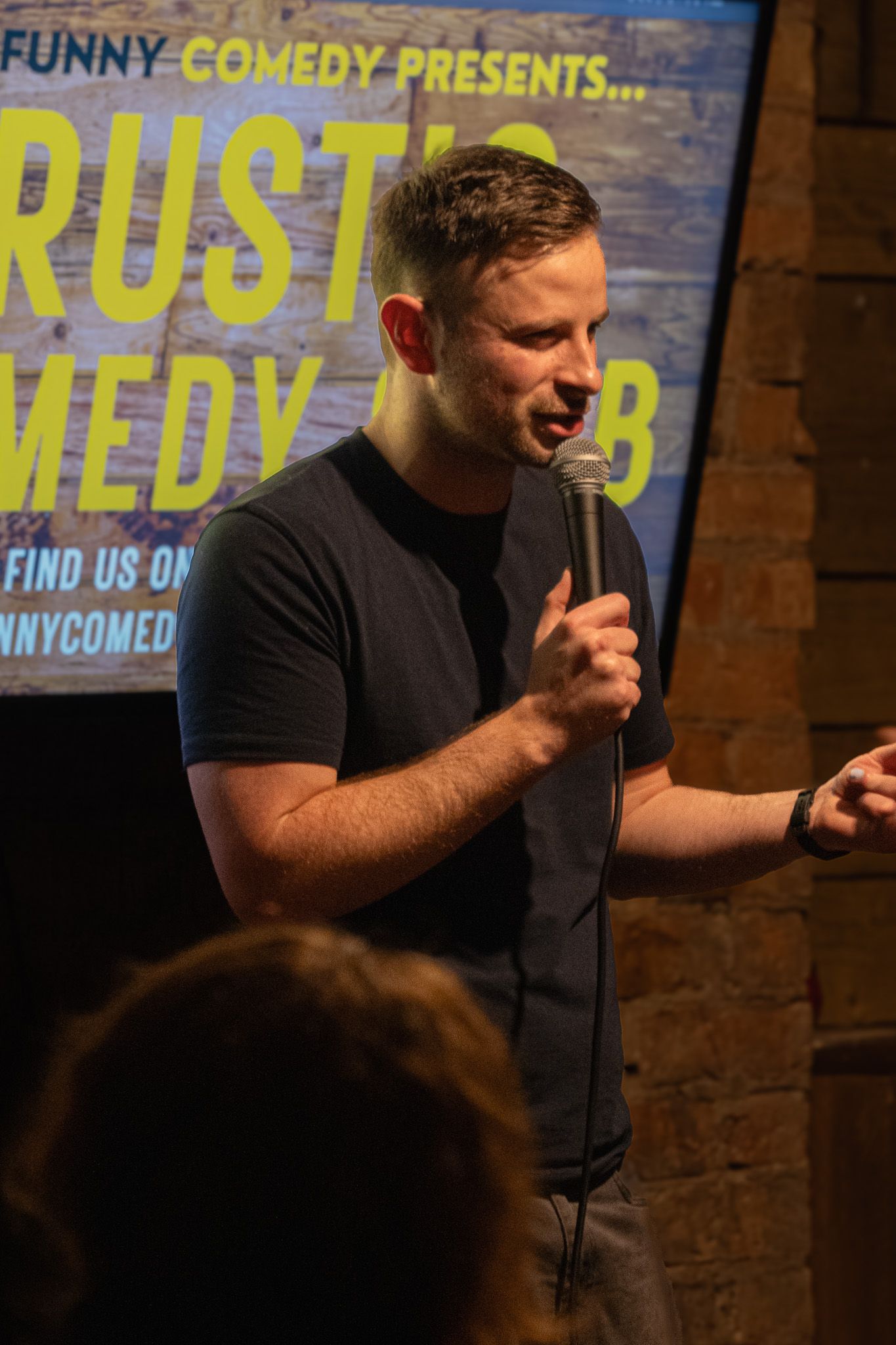 Stand-up comedian performing on stage at Trust Comedy Club.
