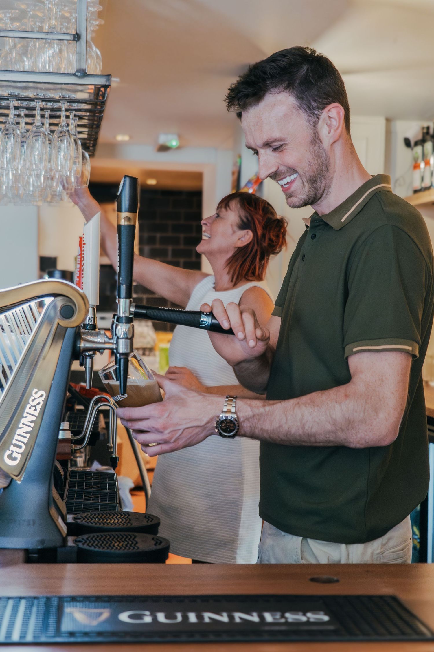 Brand Photography for bartenders. Pouring drinks at a pub with Guinness tap and glassware overhead.