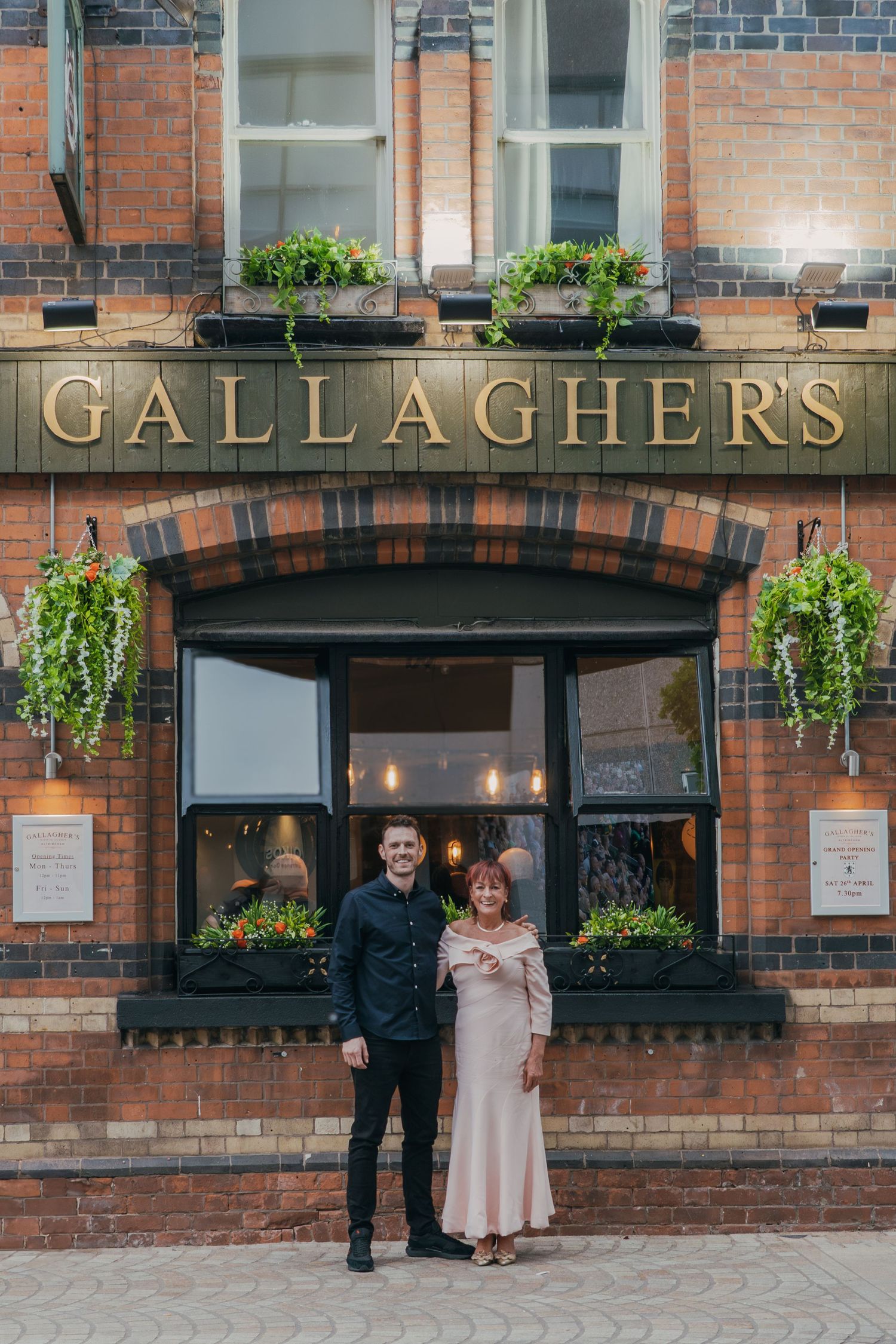 Exterior of Gallagher's pub with red brick facade and decorative window boxes filled with greenery.