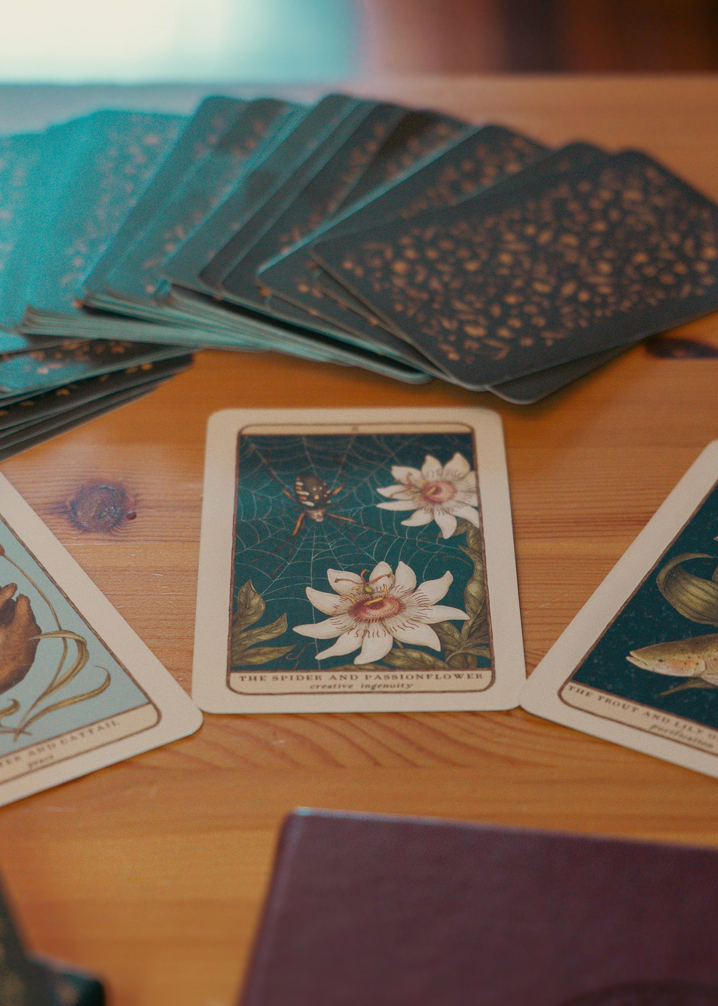 Tarot cards with floral designs spread out on wooden table surface.