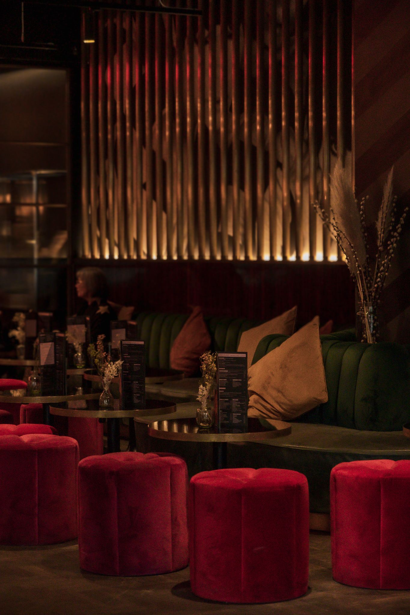 Luxurious lounge interior with red velvet poufs and green velvet seating.