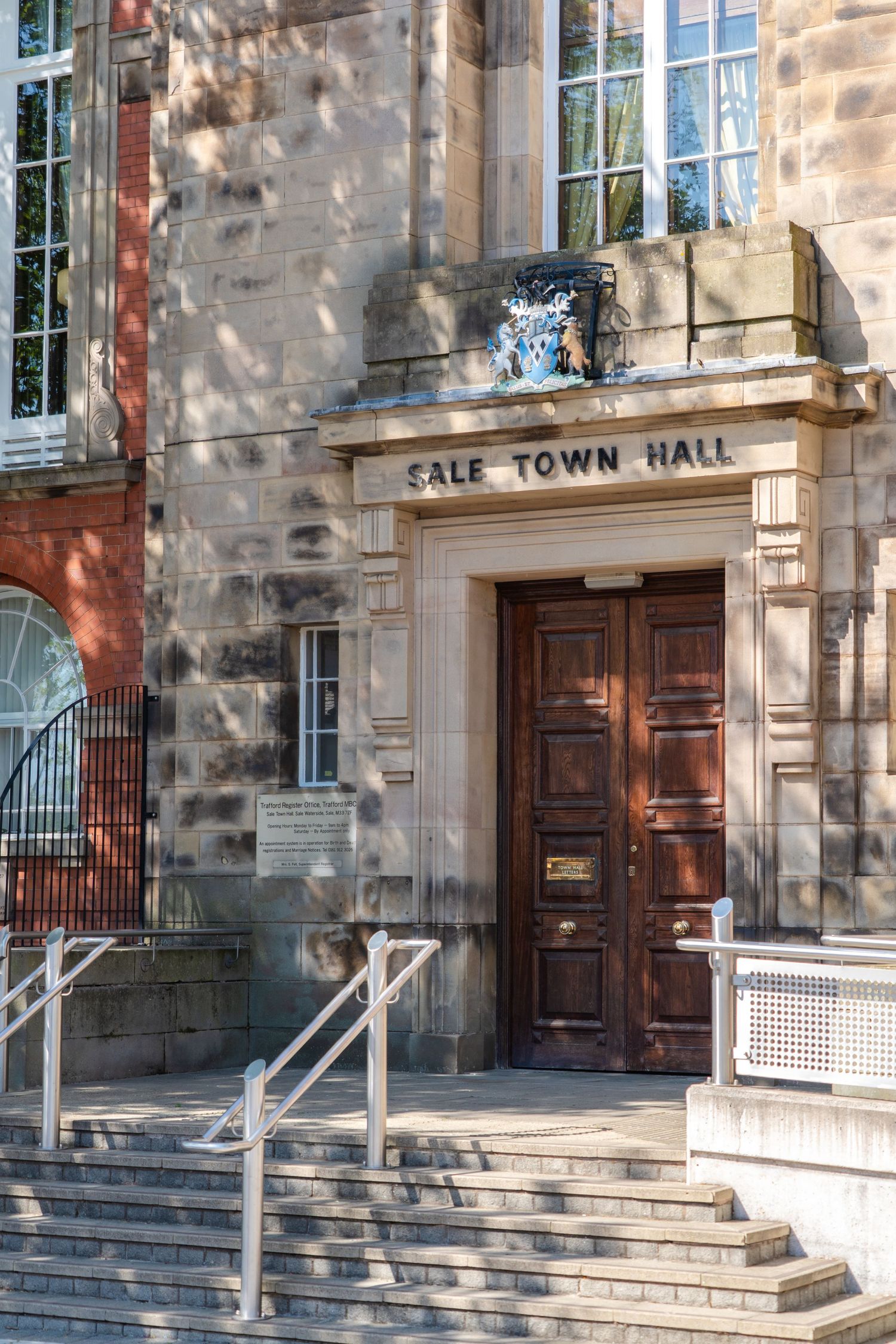 Historic entrance to Sale Town Hall with wooden door, stone steps, and handrails leading to the main doorway.