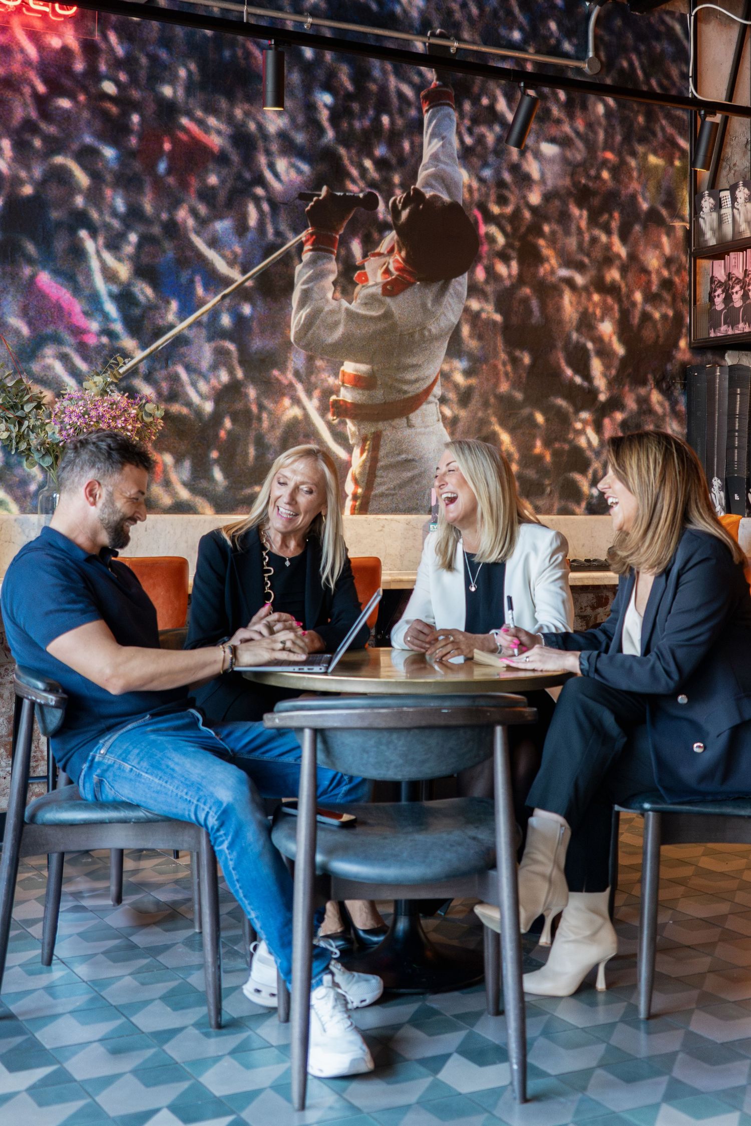 Group of business colleagues having casual meeting at restaurant table with wall mural backdrop.