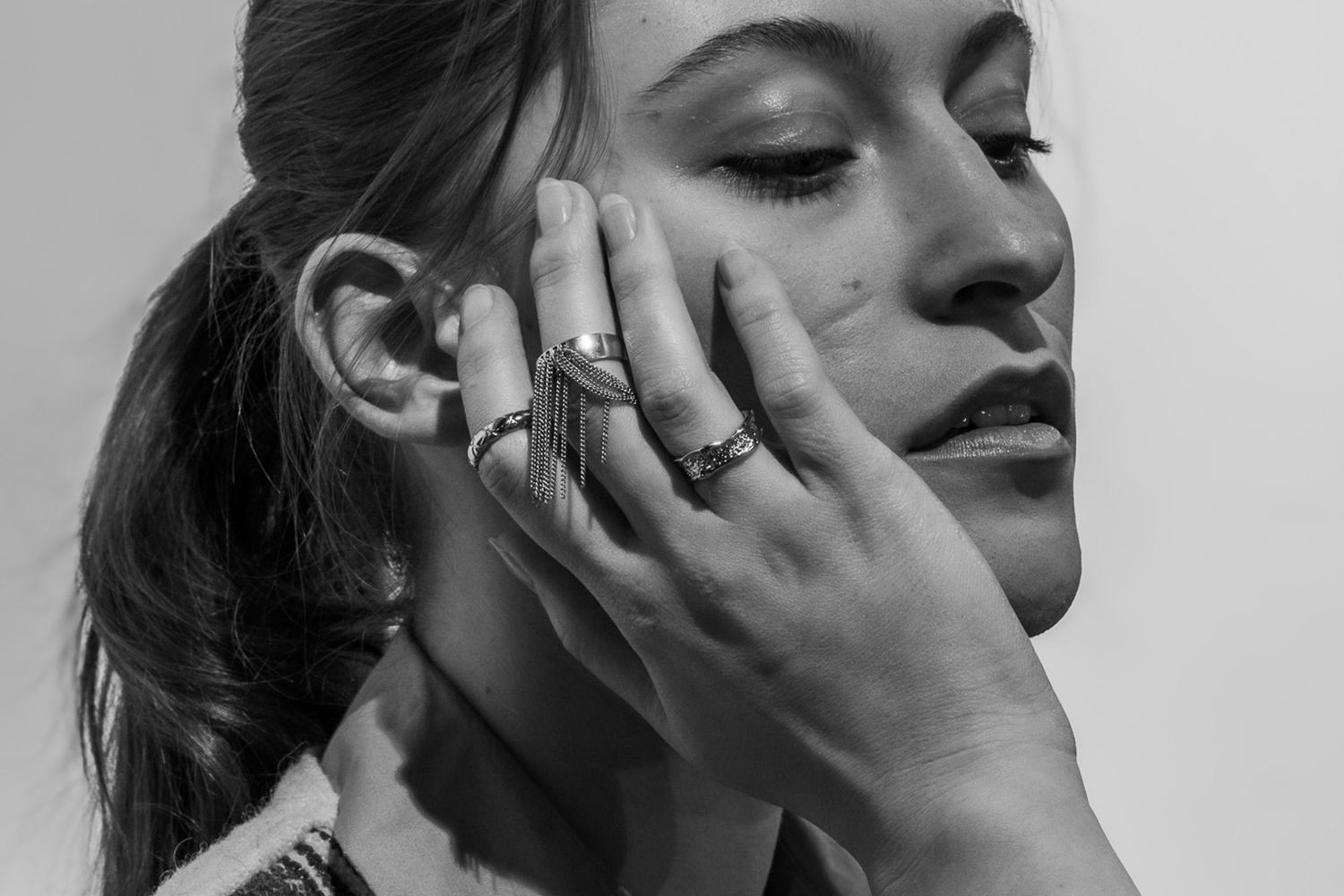 Black and white artistic portrait highlighting silver jewelry and fashion styling.