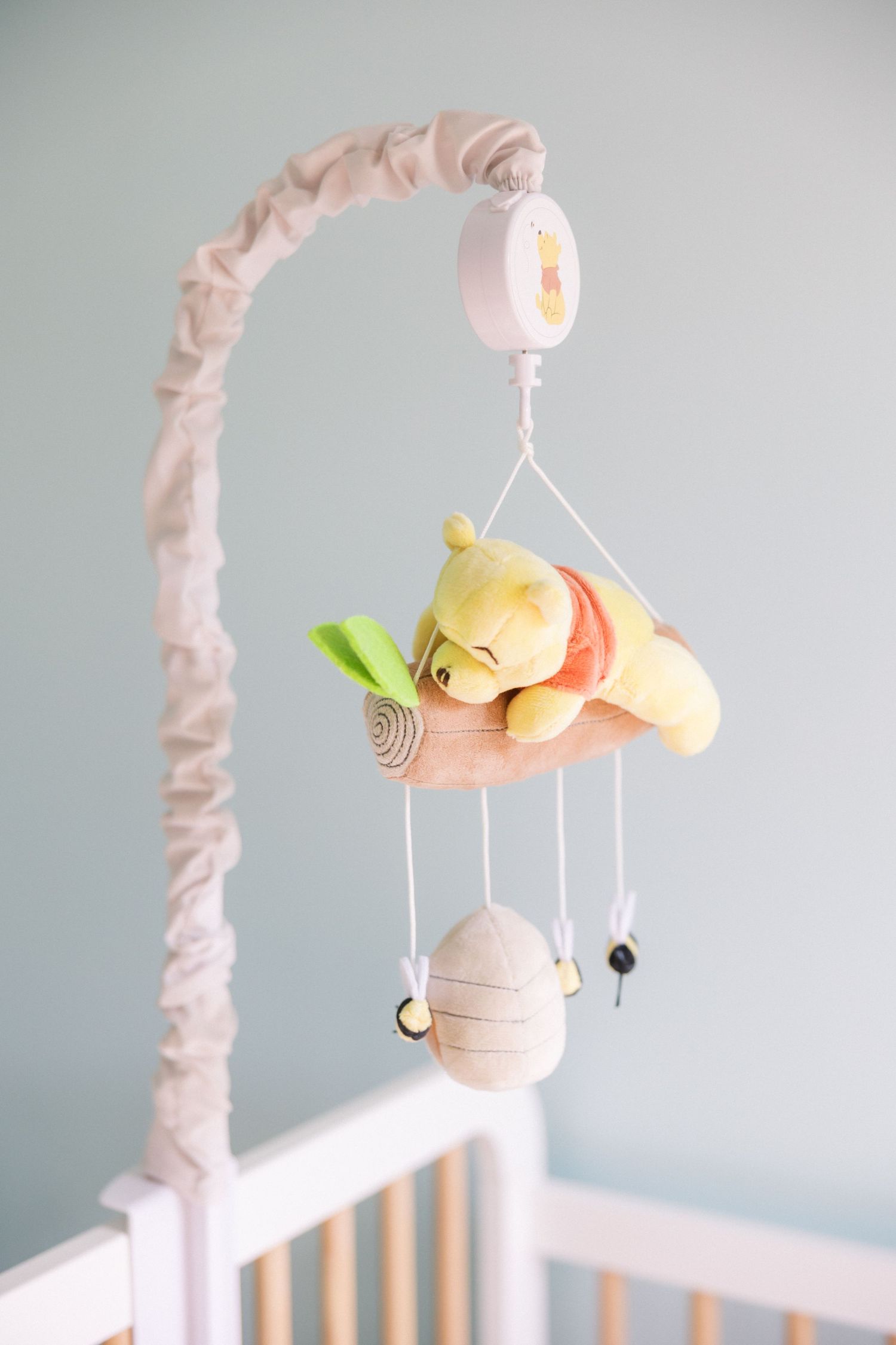 Plush animal baby mobile with soft toys hanging over white crib.