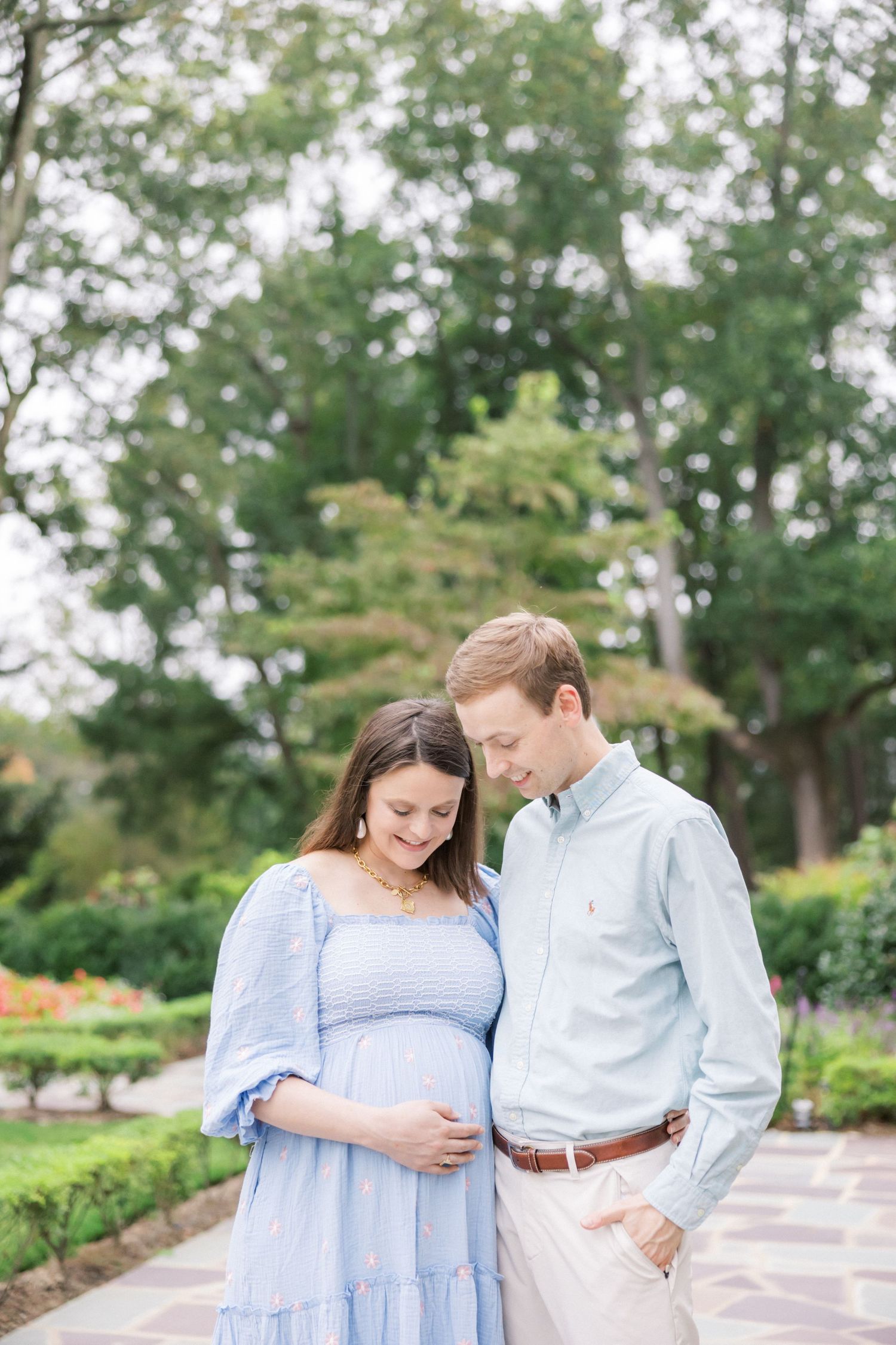 Tender moment captured on garden path with couple in coordinated blue and white outfits.