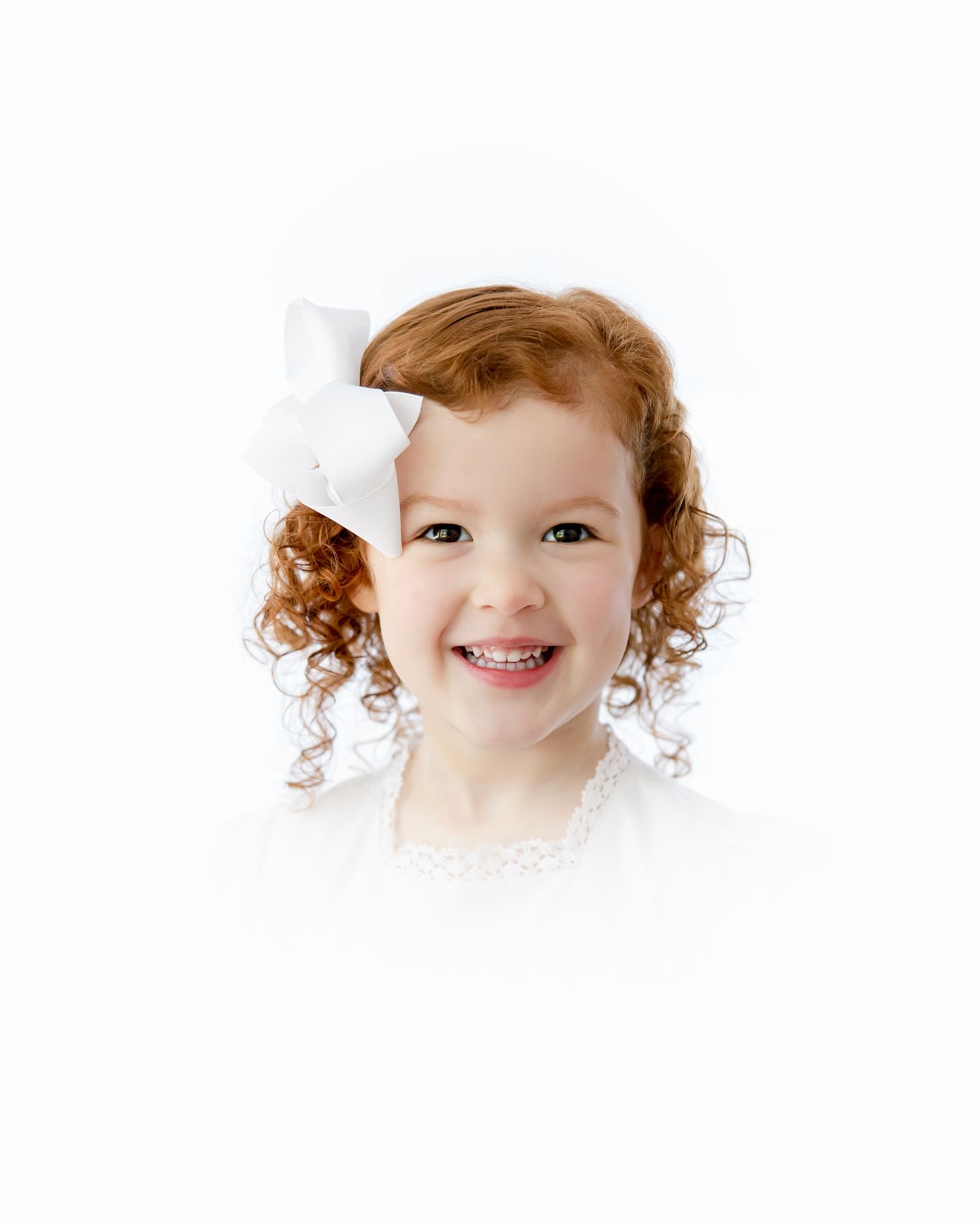 Joyful expression captured in portrait with natural curls and white attire on clean background.